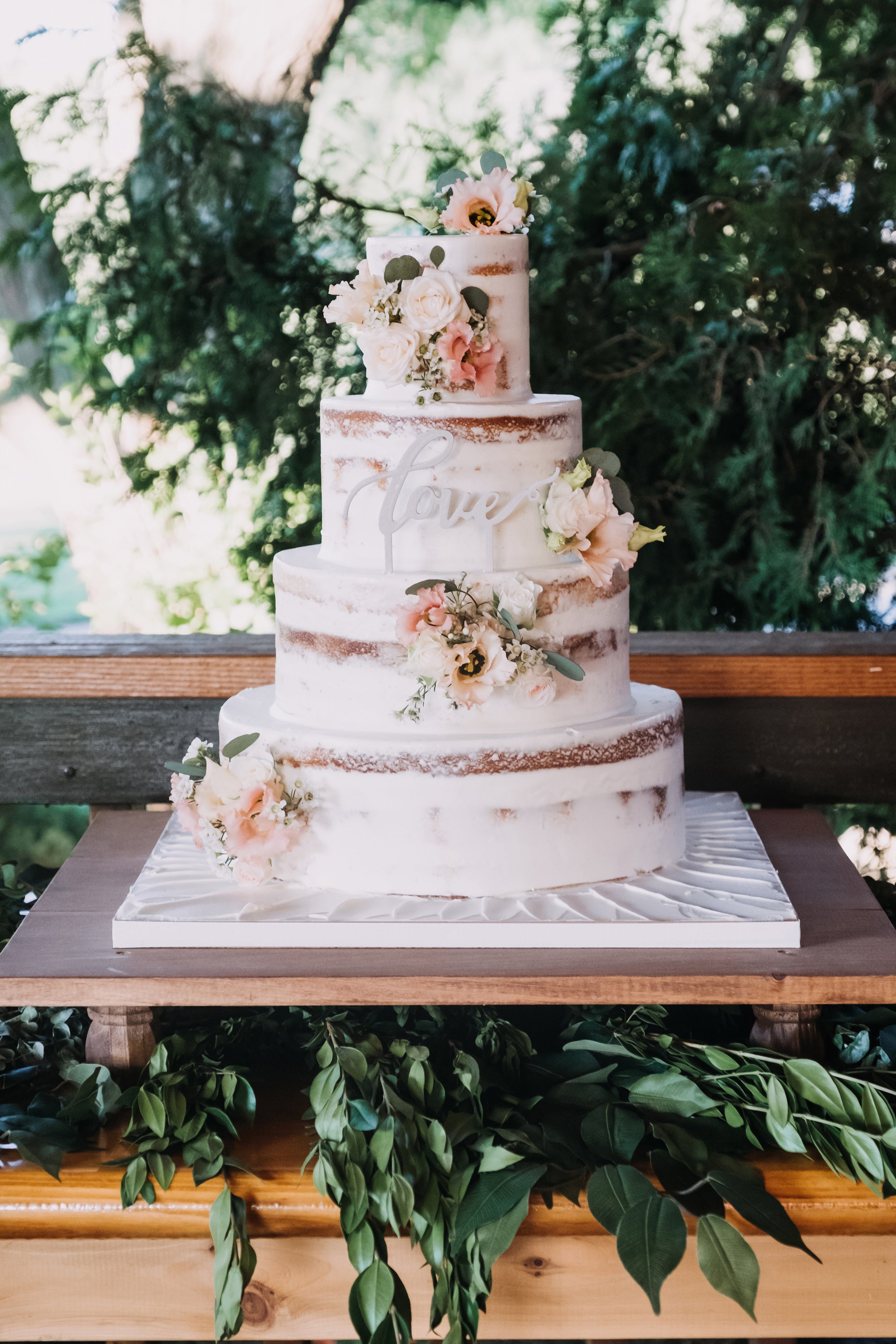 Wedding cake decorated with flowers and &quot;love&quot; sign