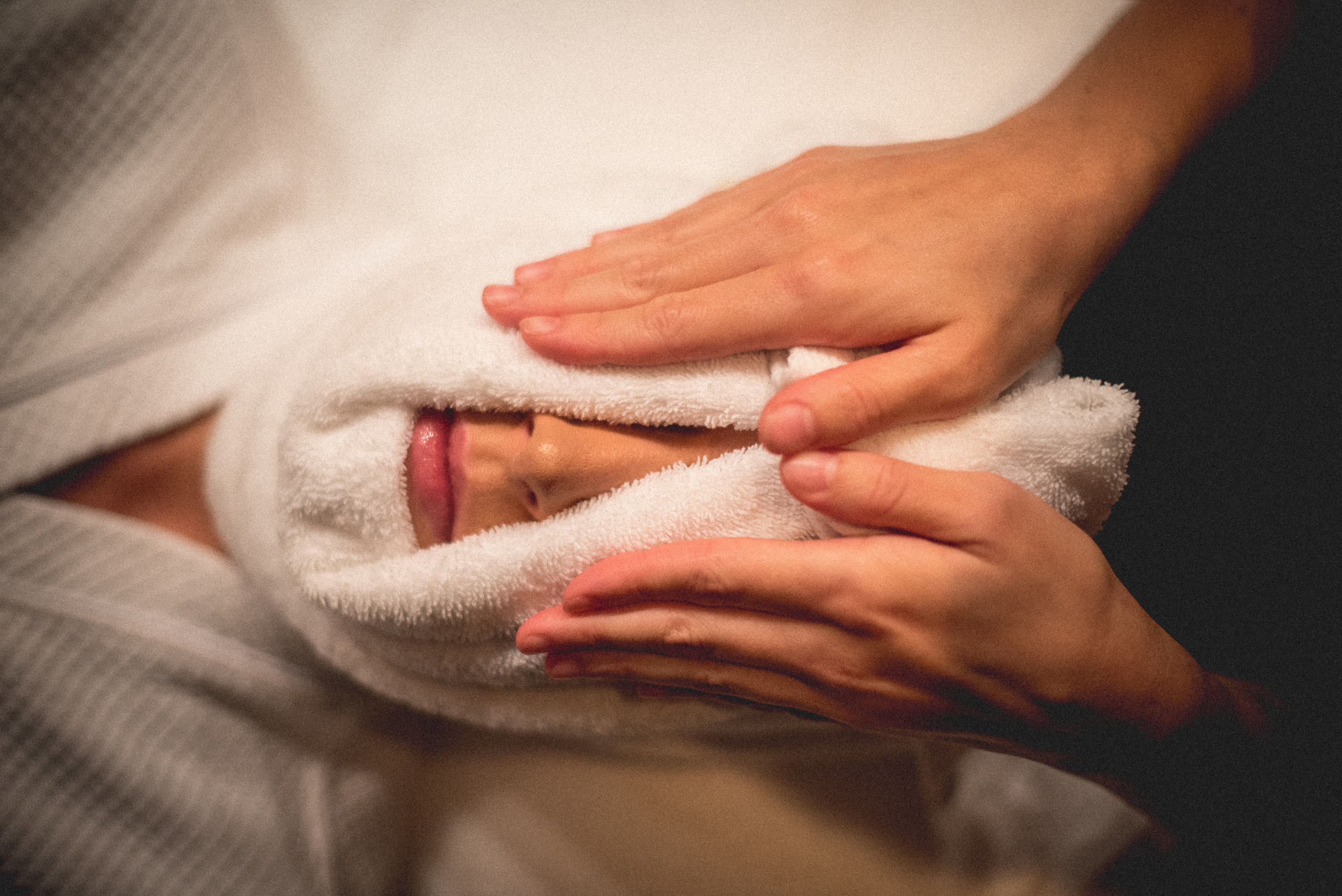 Warm towel around woman's face.