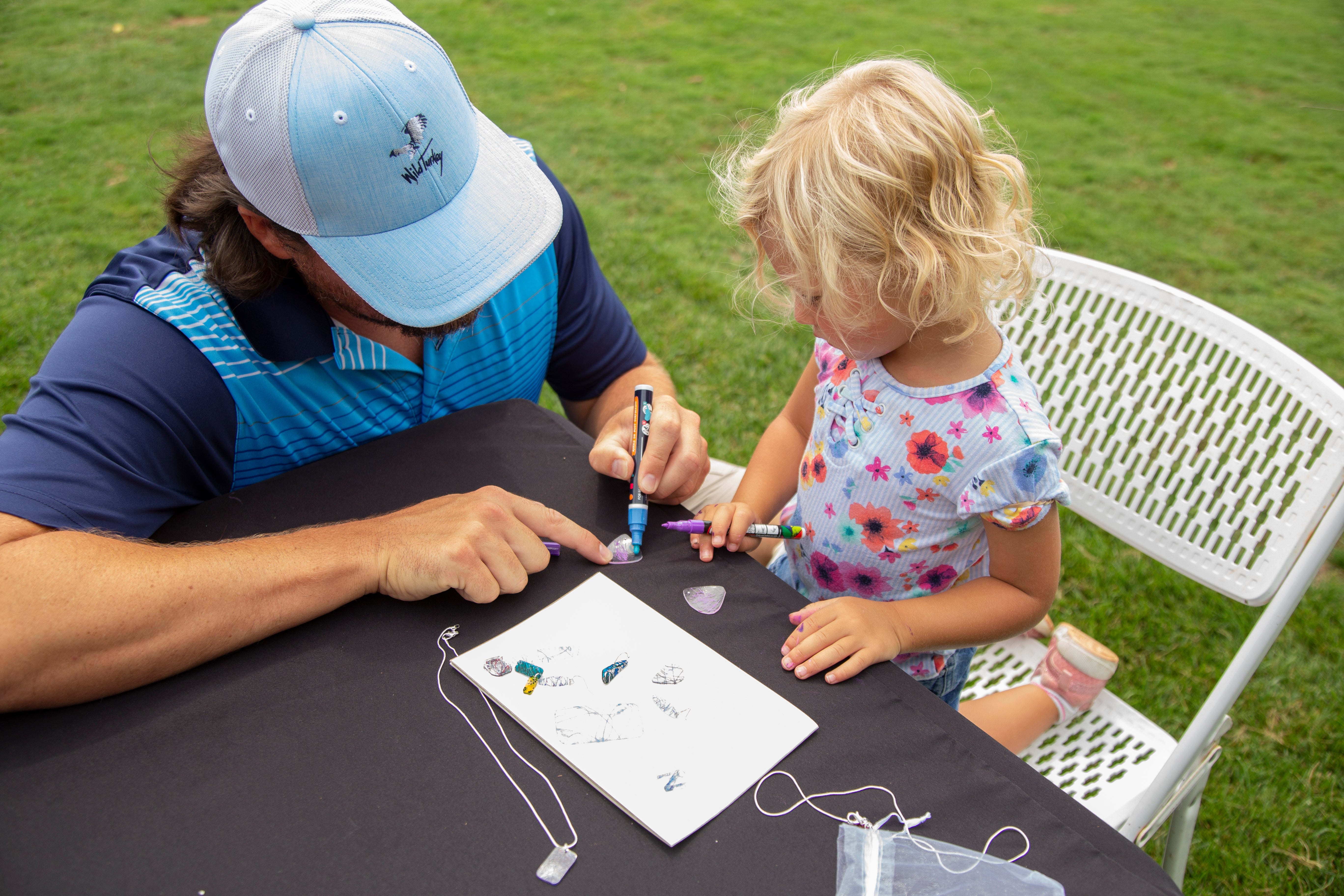 Adult helping child make shrinky jewelry