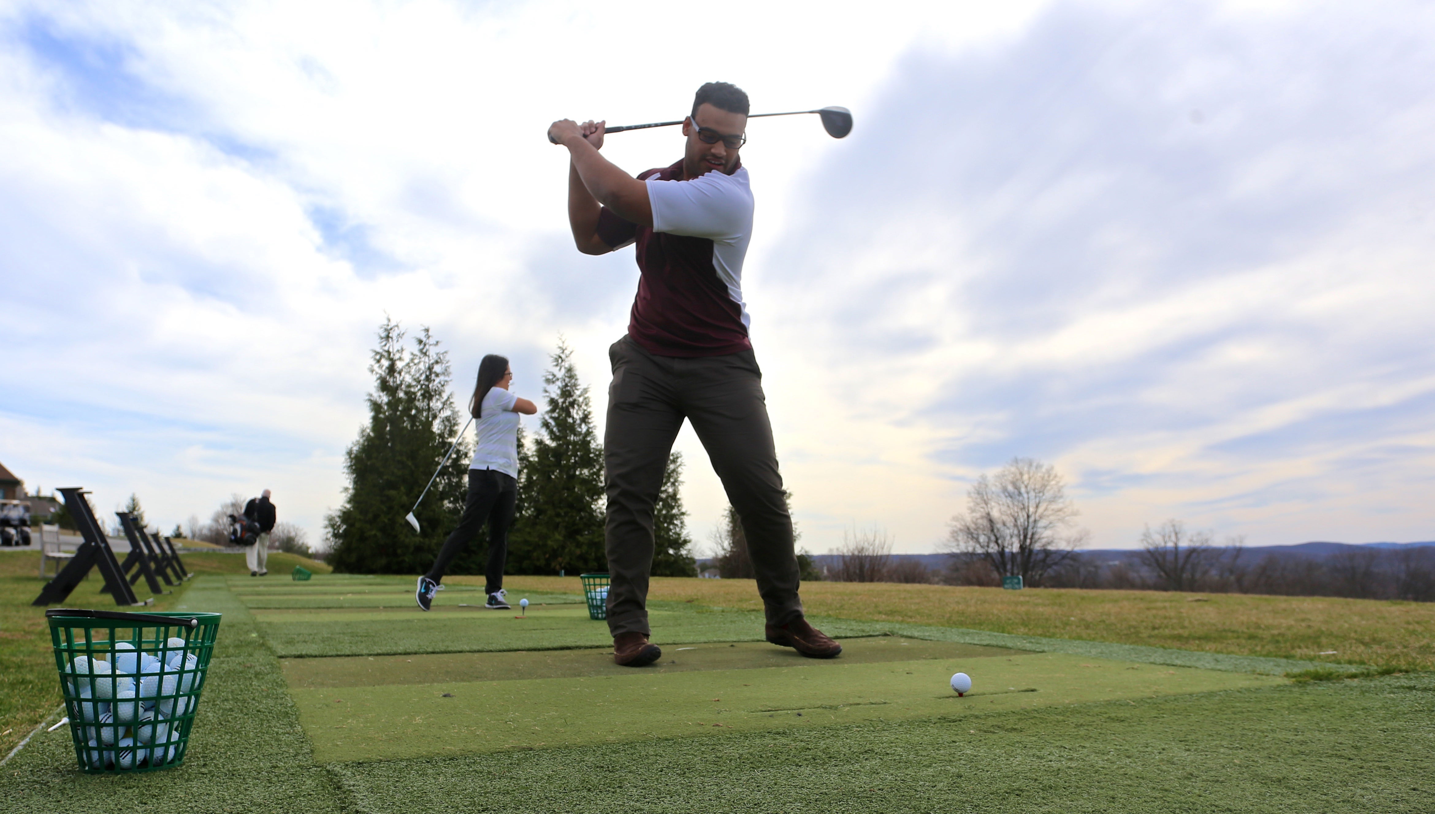 People practicing their swing at the driving range.