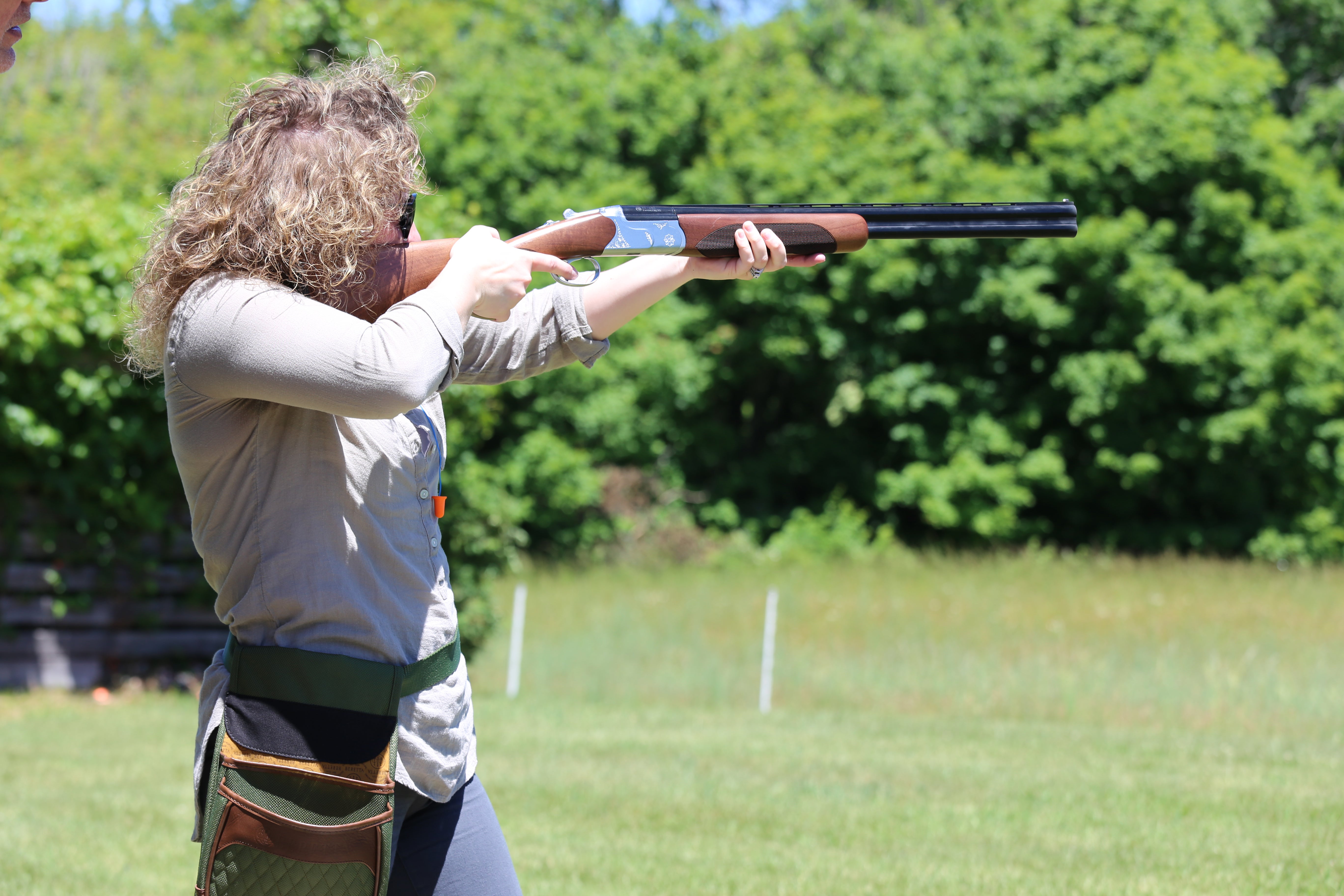 Woman shooting laser gun at clay targets.