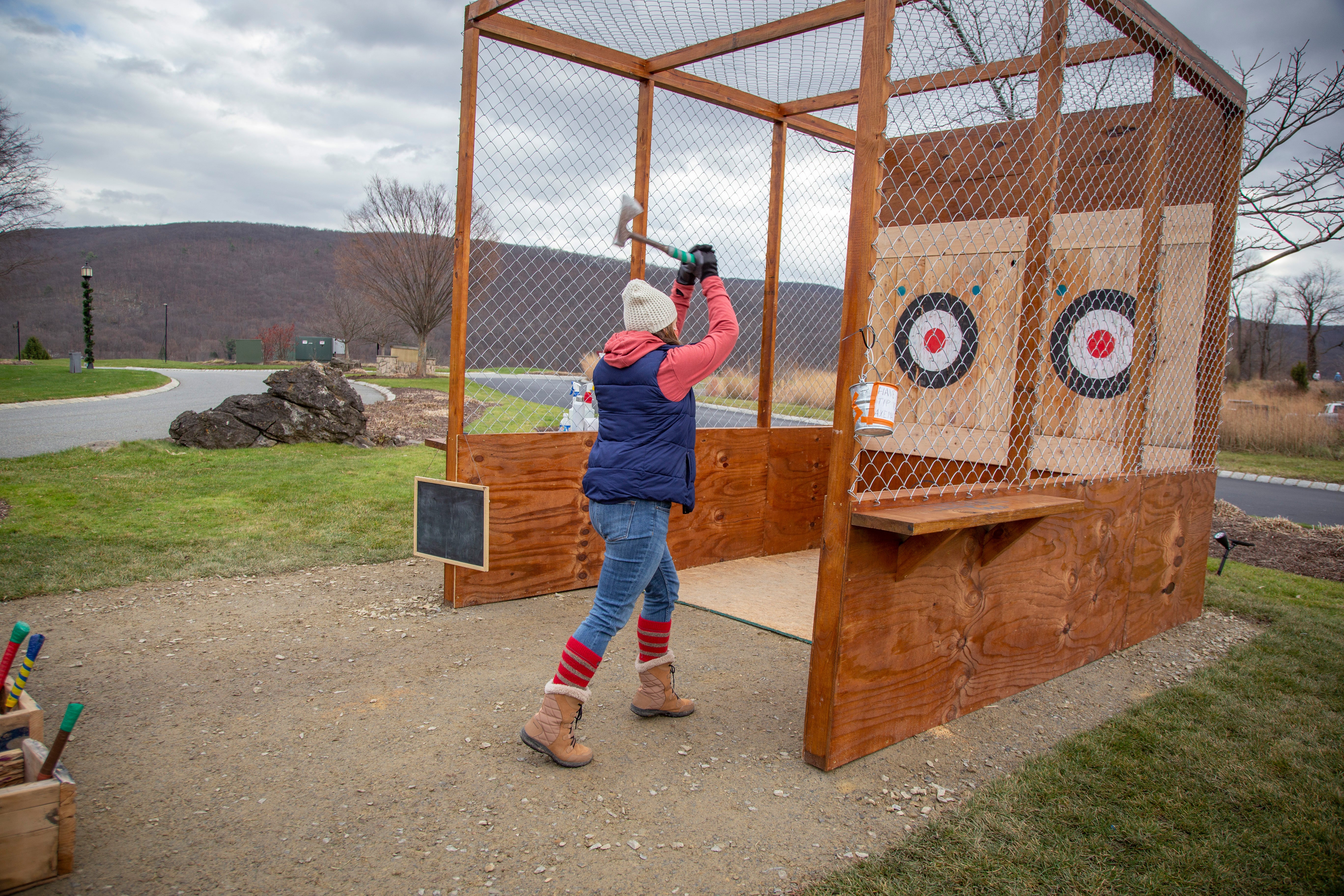 Woman throwing axe at target.