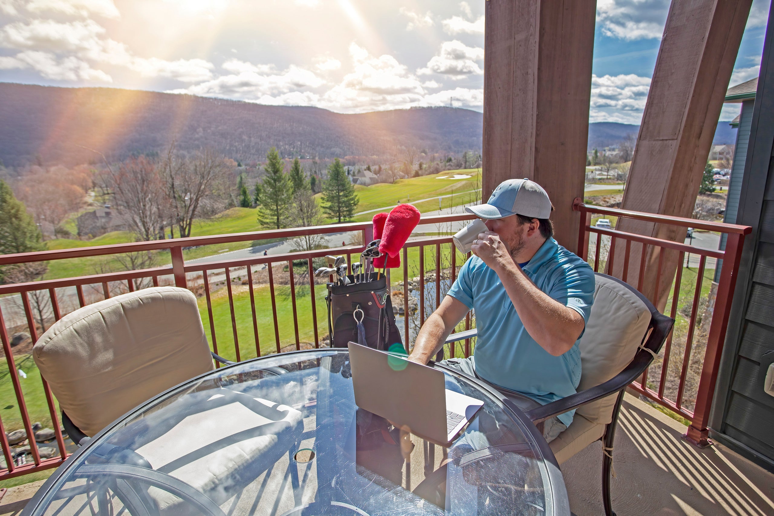 Man sitting on his balcony working on his laptop at Grand Cascades Lodge