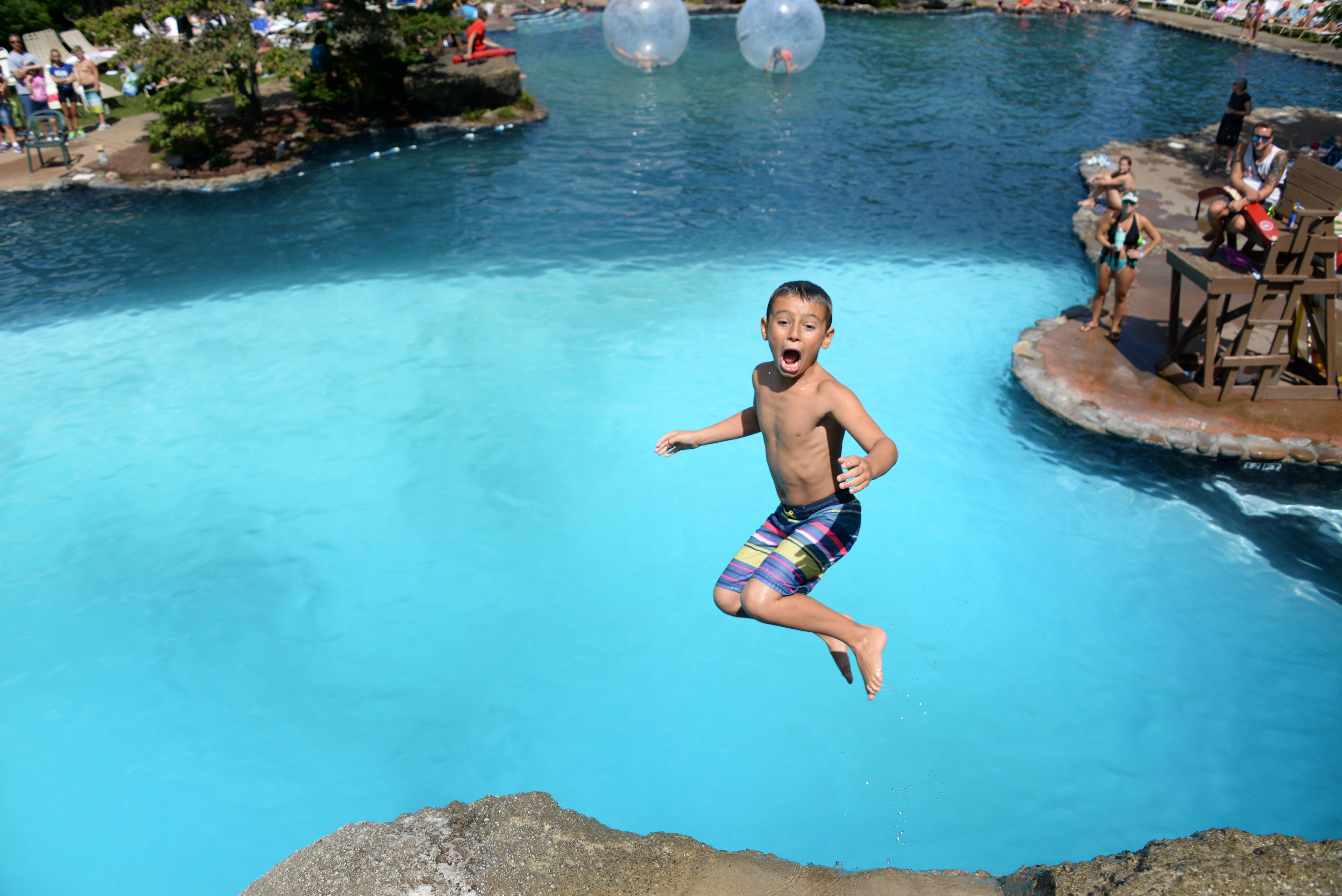 Young boy jumping off cliff at Minerals Hotel pool. 