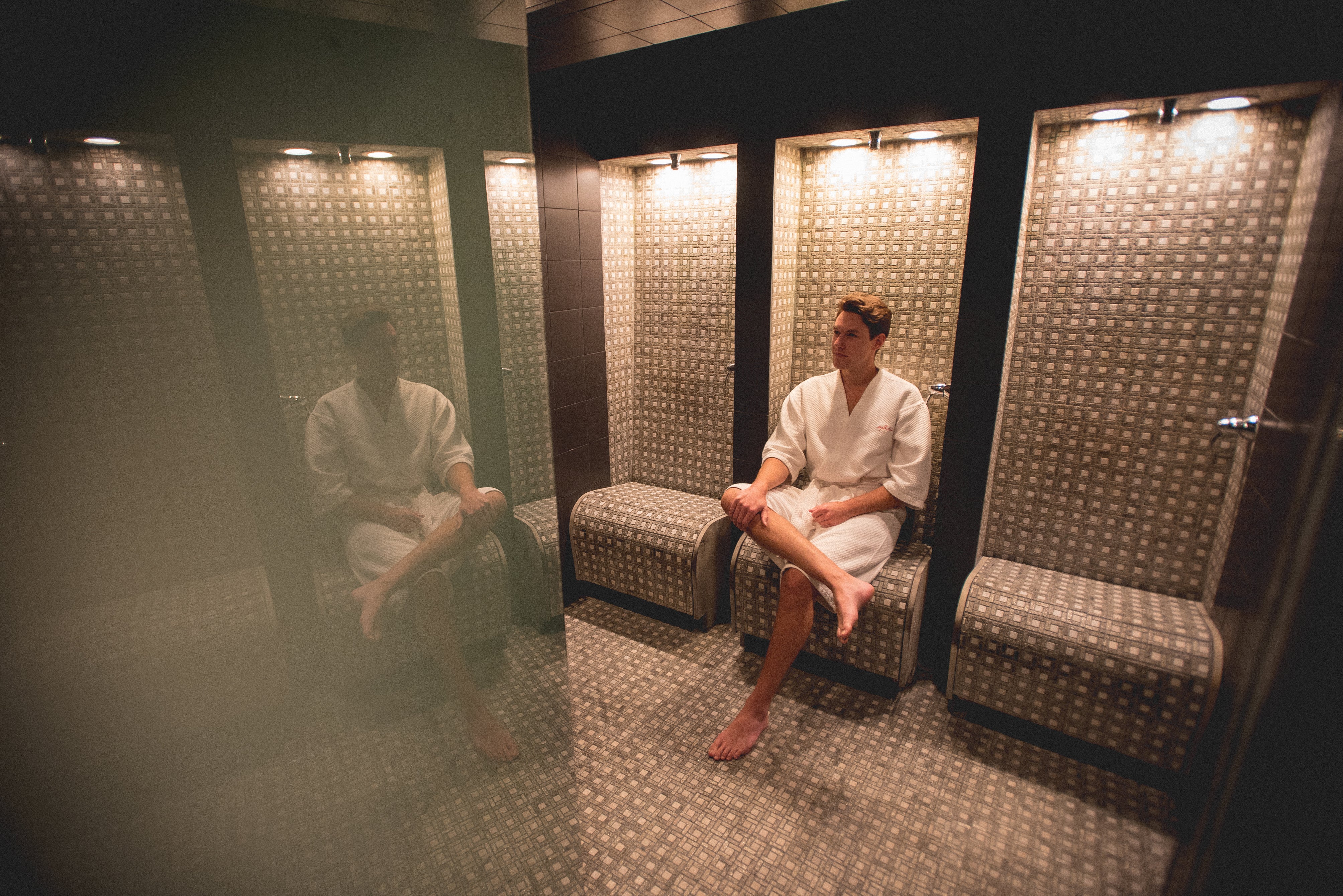 Man in white bath robe sitting in sauna.