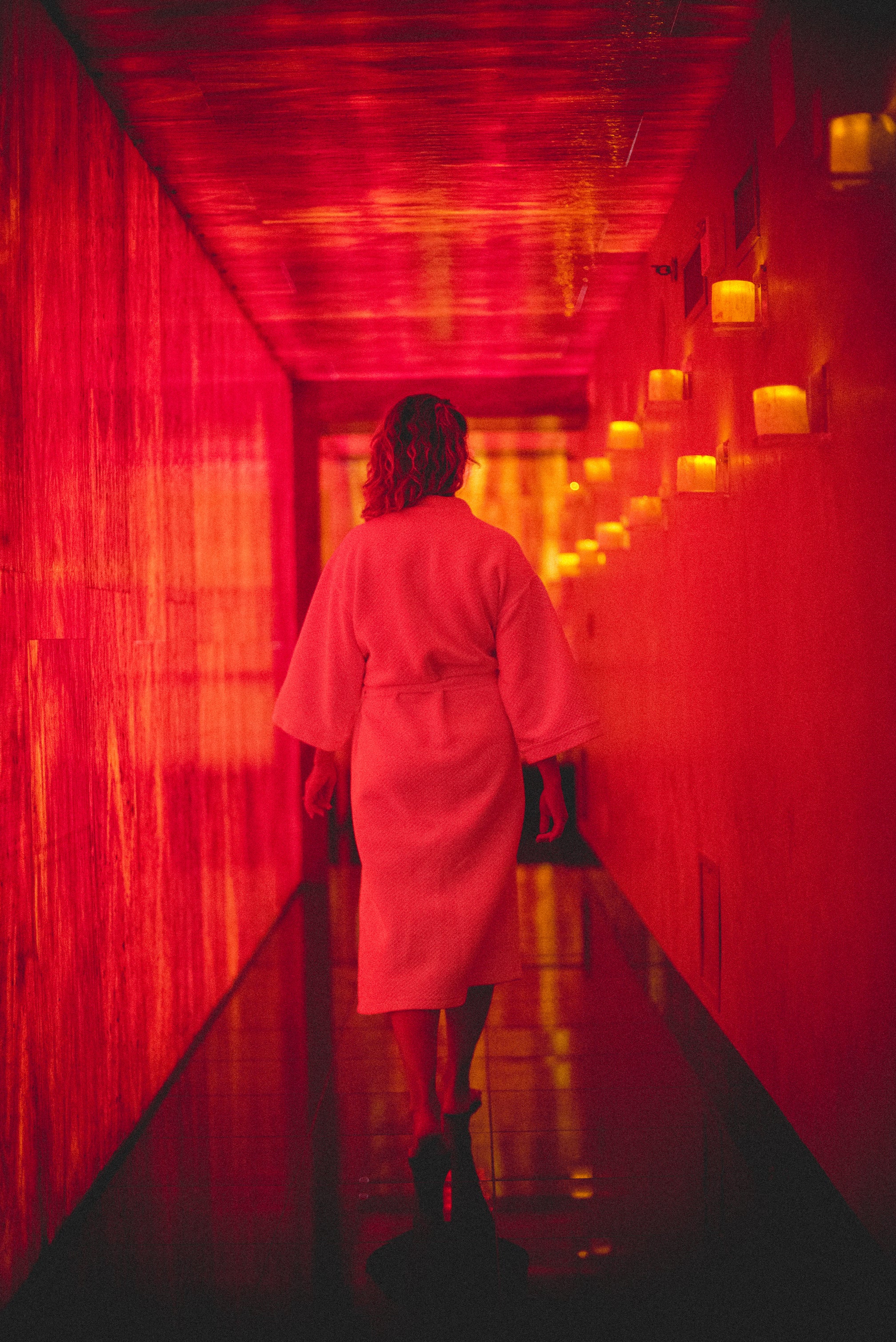 Woman in white robe walking down Reflections Spa hallway.