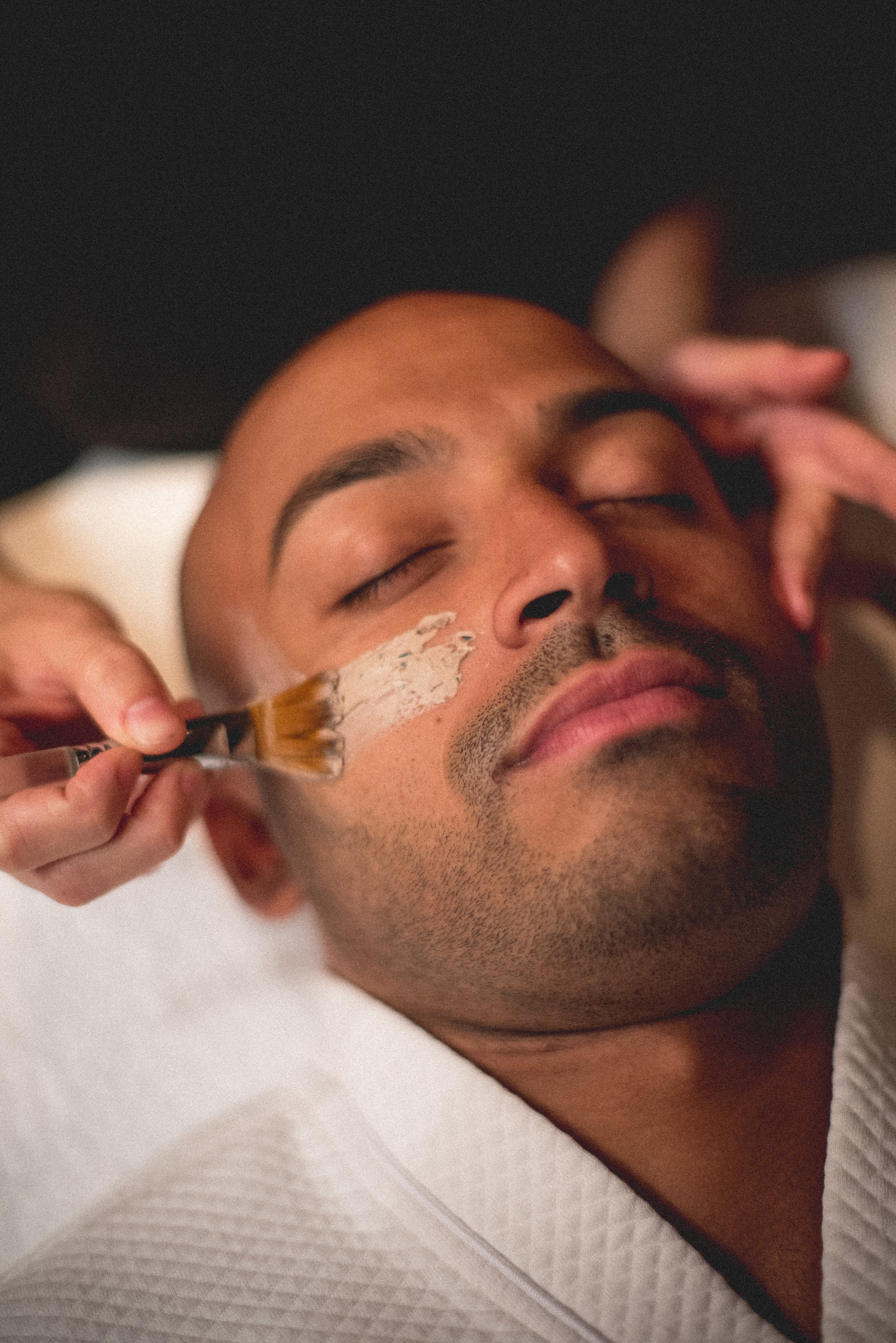 Mask being applied to man's face during facial
