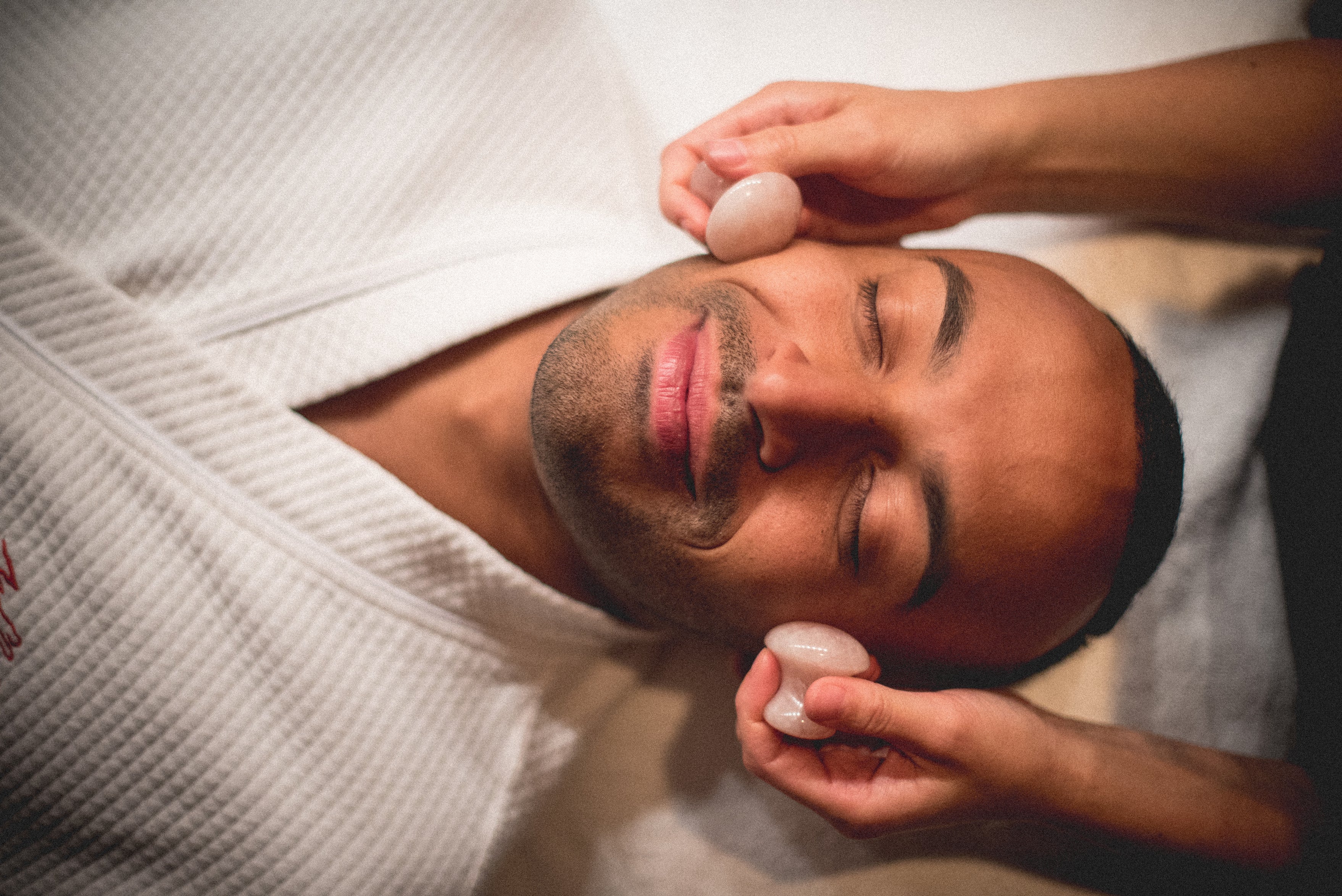 Man receiving rose quartz facial