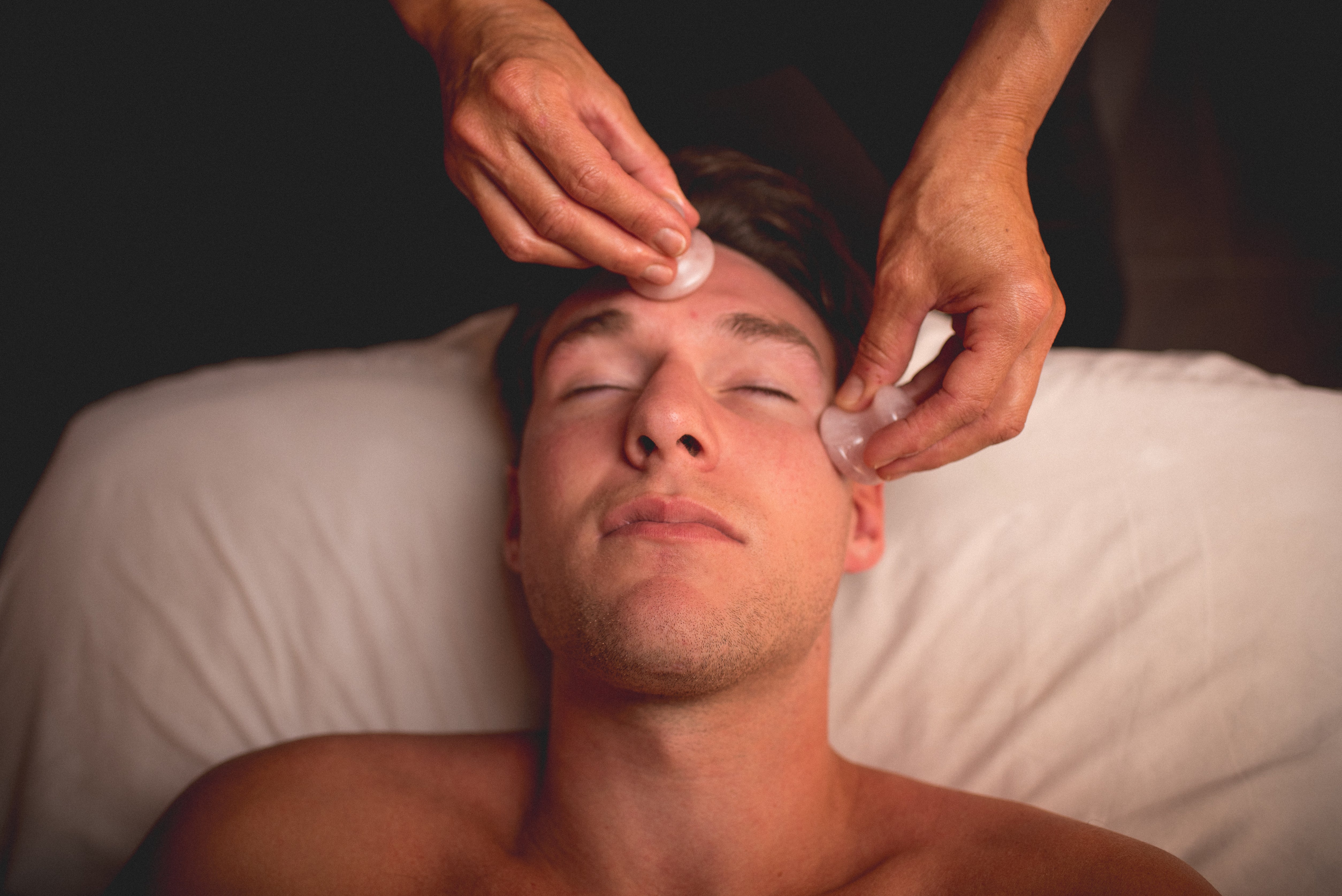 Male receiving rose quartz facial