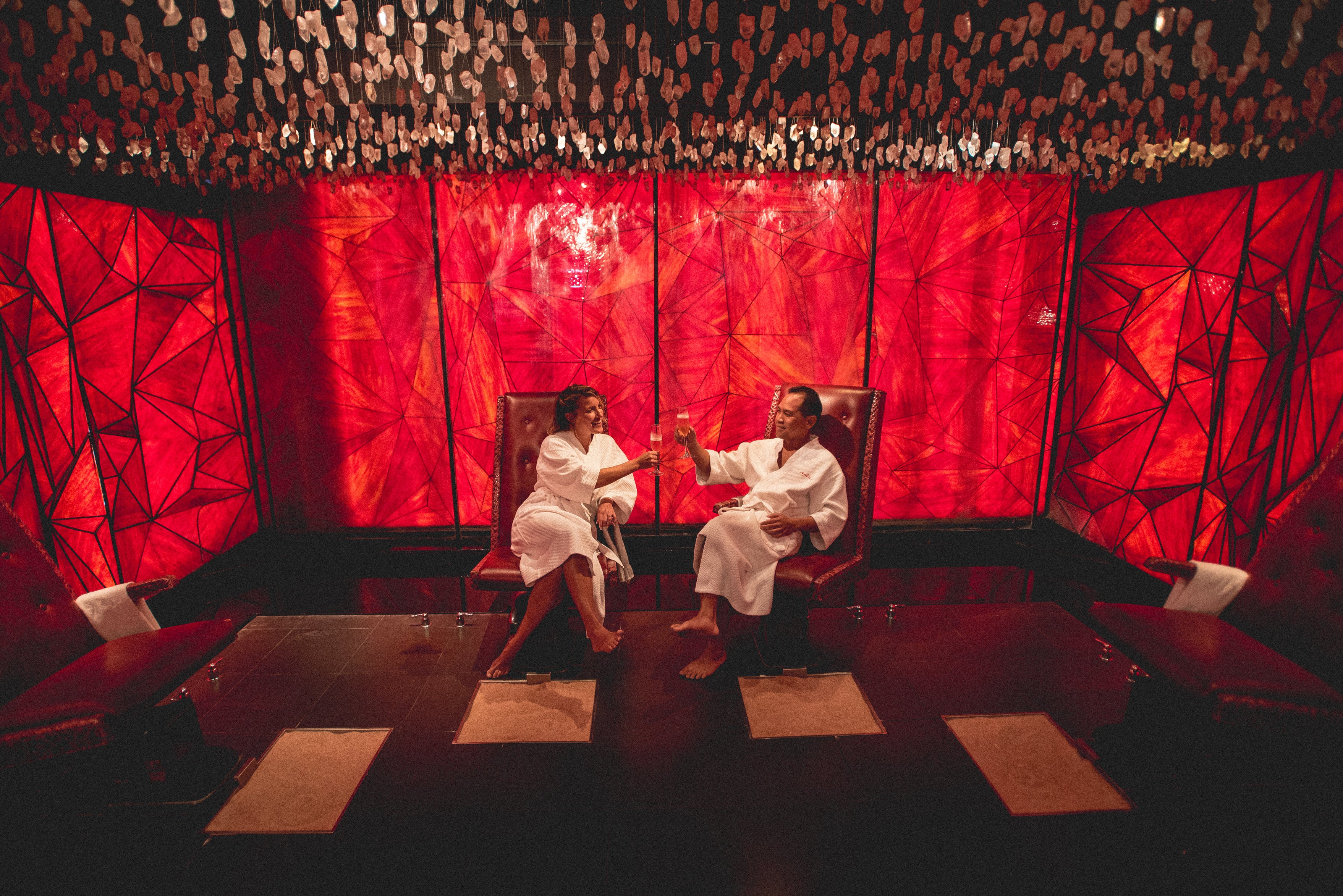 Couple sitting in Reflections Spa salt room cheersing champagne