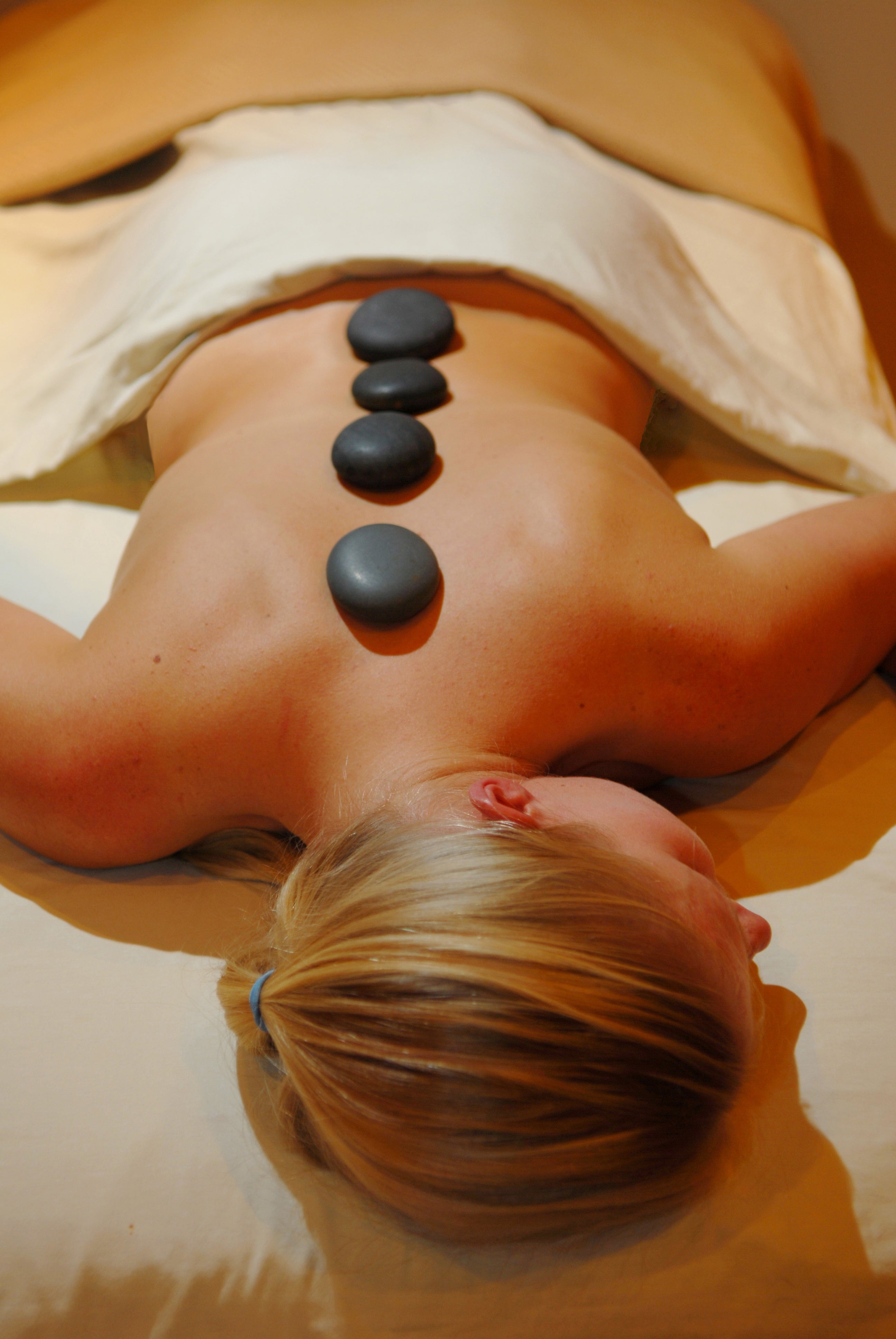 Woman laying with hot stones down the middle of her back.