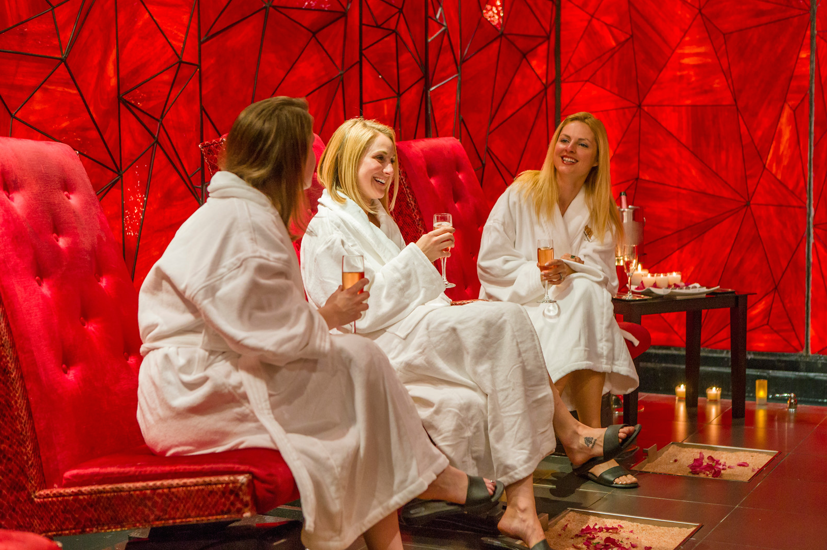 Group of girlfriends in white robes drinking champagne in Reflections Spa's Crystal Room.
