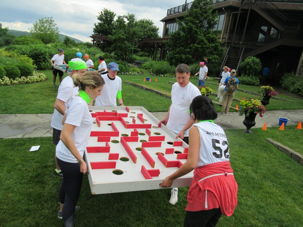 Adults helping each other in a teambuilding activity