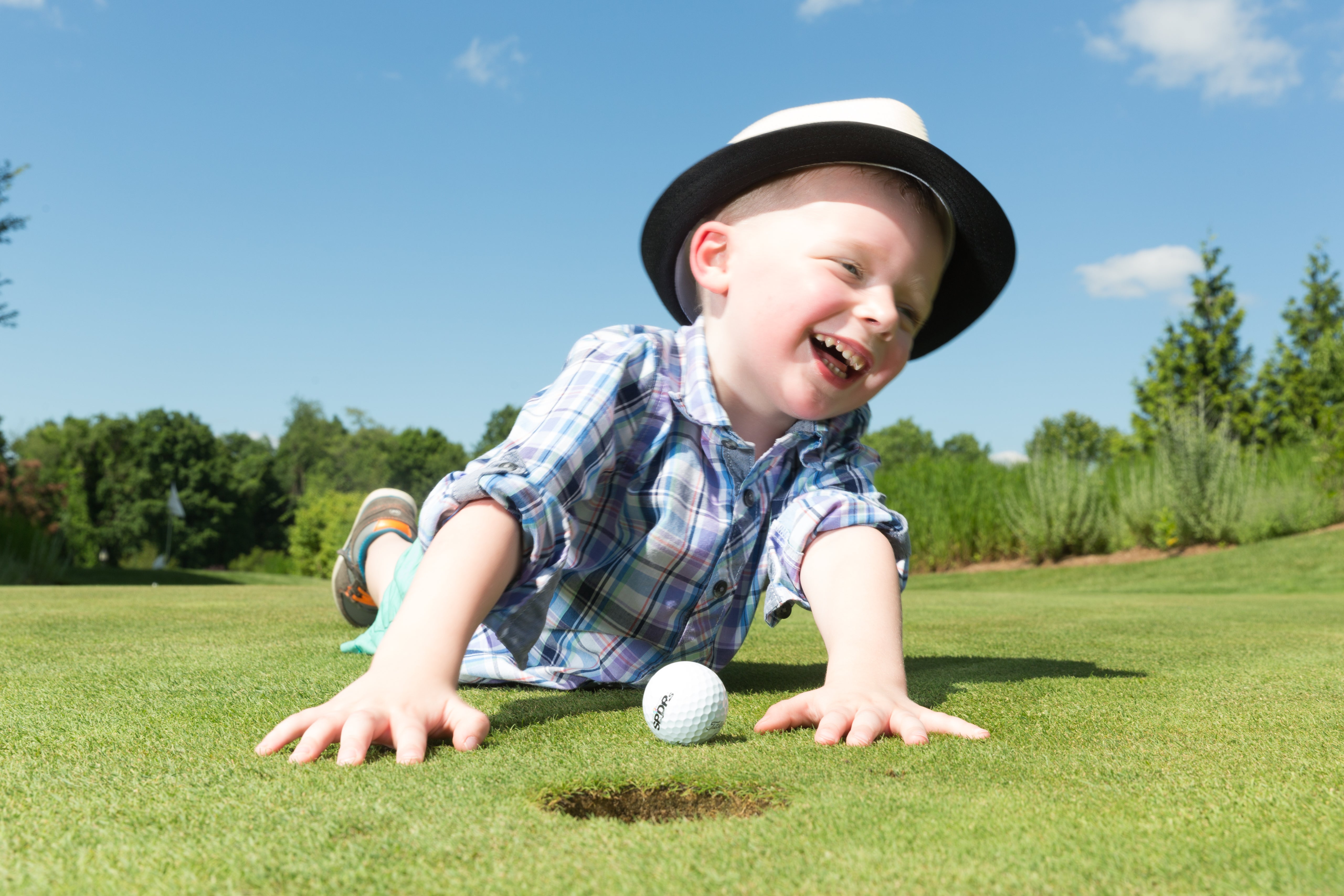 Boy smiling and laying on a golf course