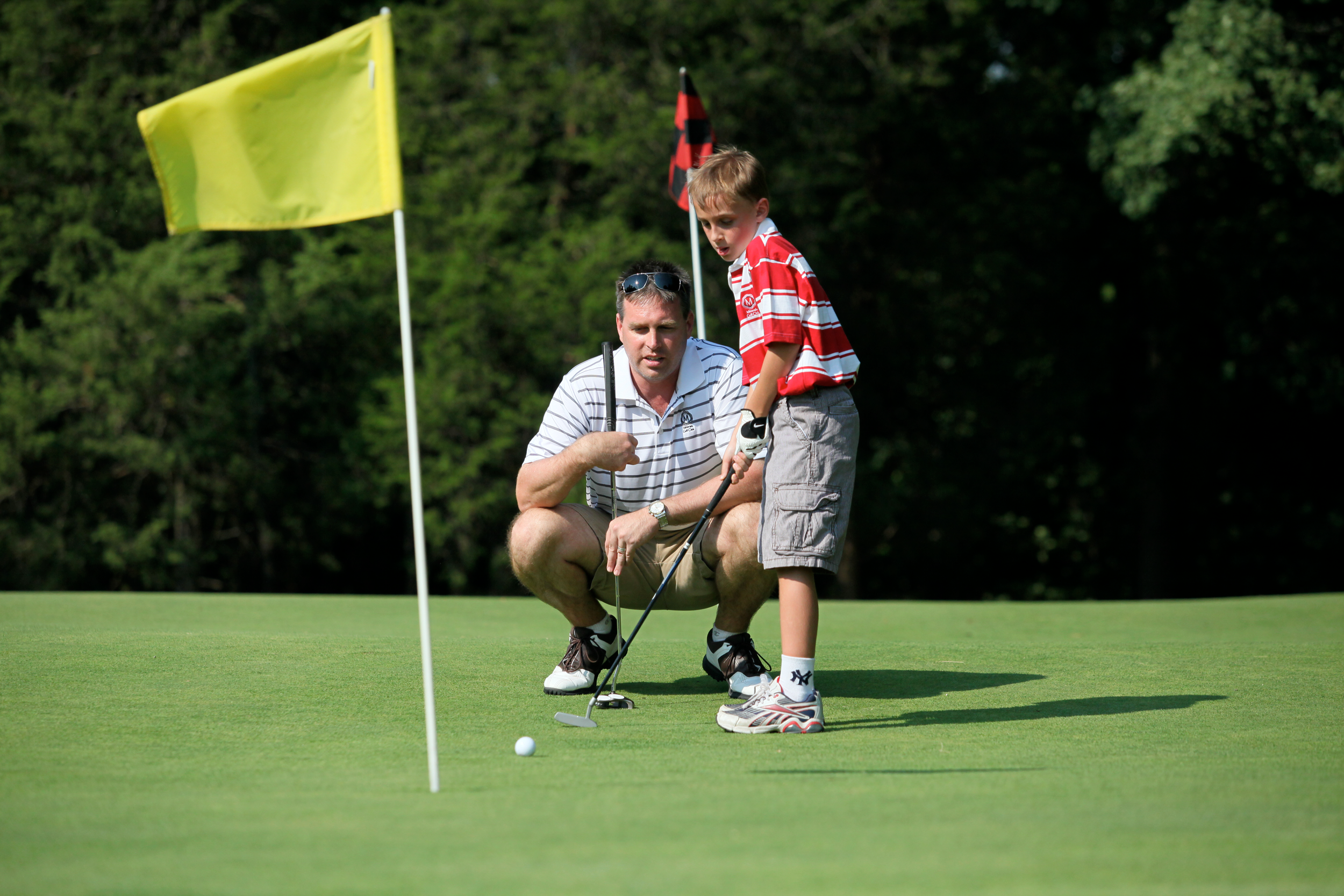 Father teaching his young son to golf at a resort near NYC
