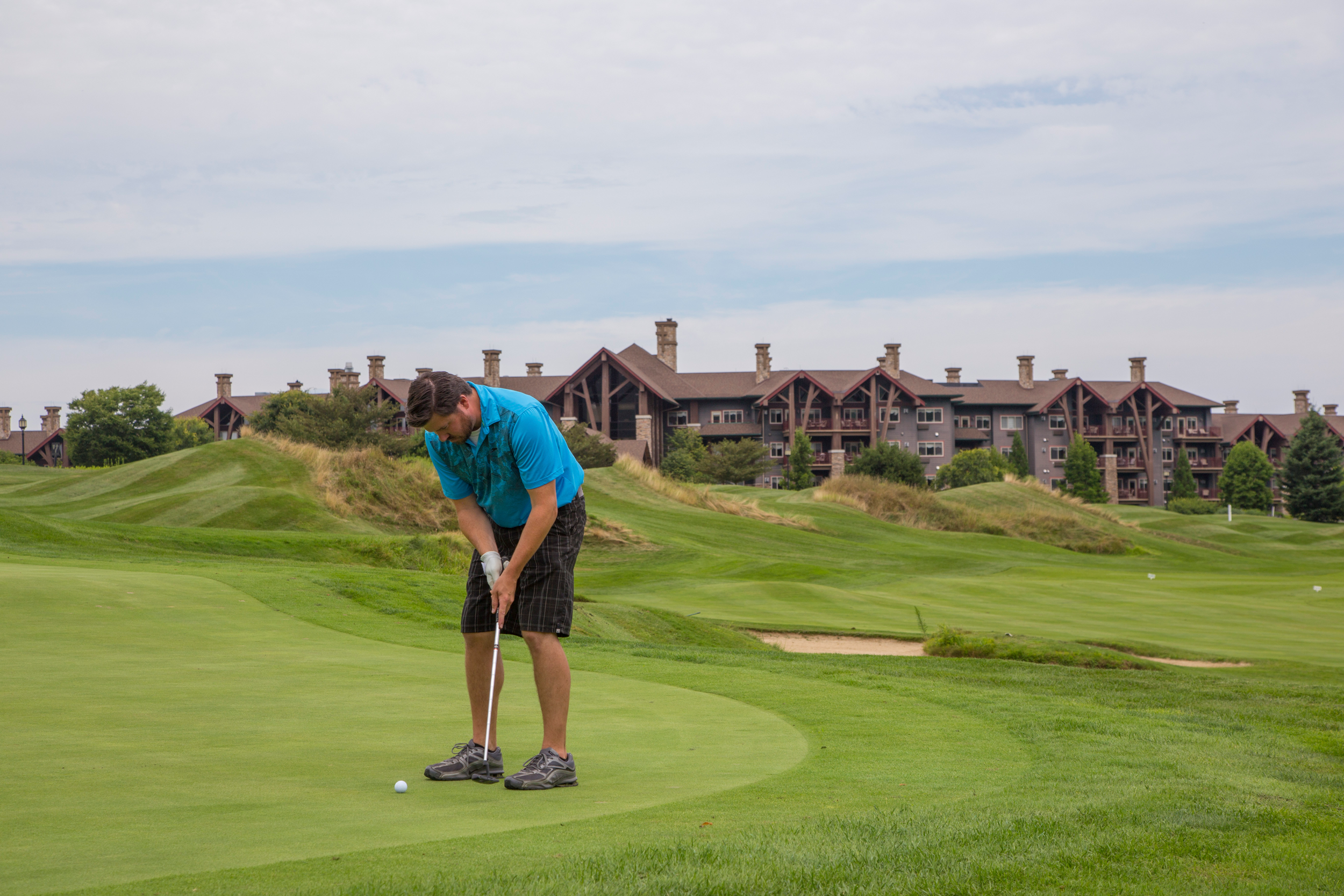 Man wearing a blue shirt putting on a green at the Crystal Springs Golf Course