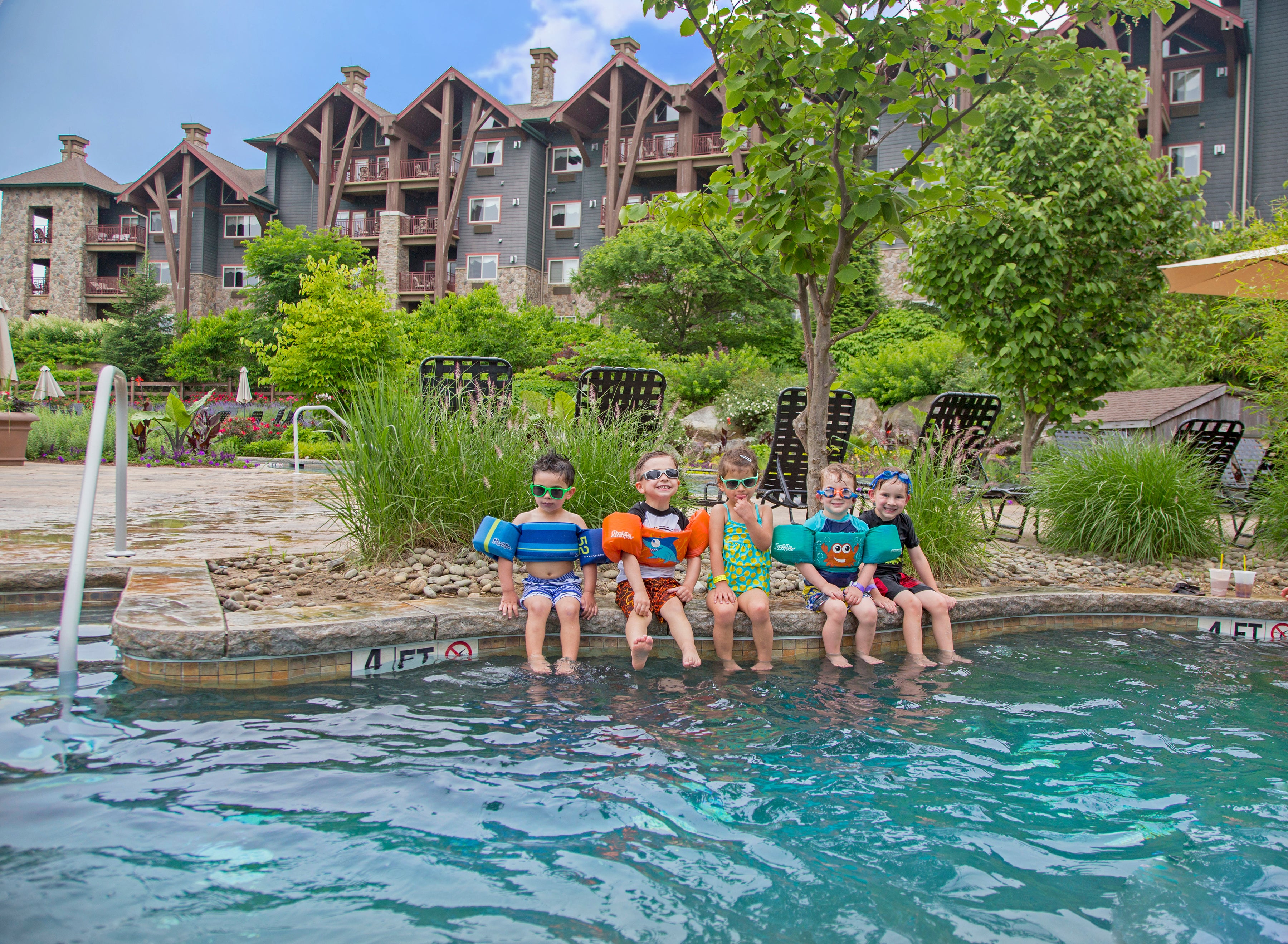 Children with floaties on sitting on edge of outdoor Biosphere pool.