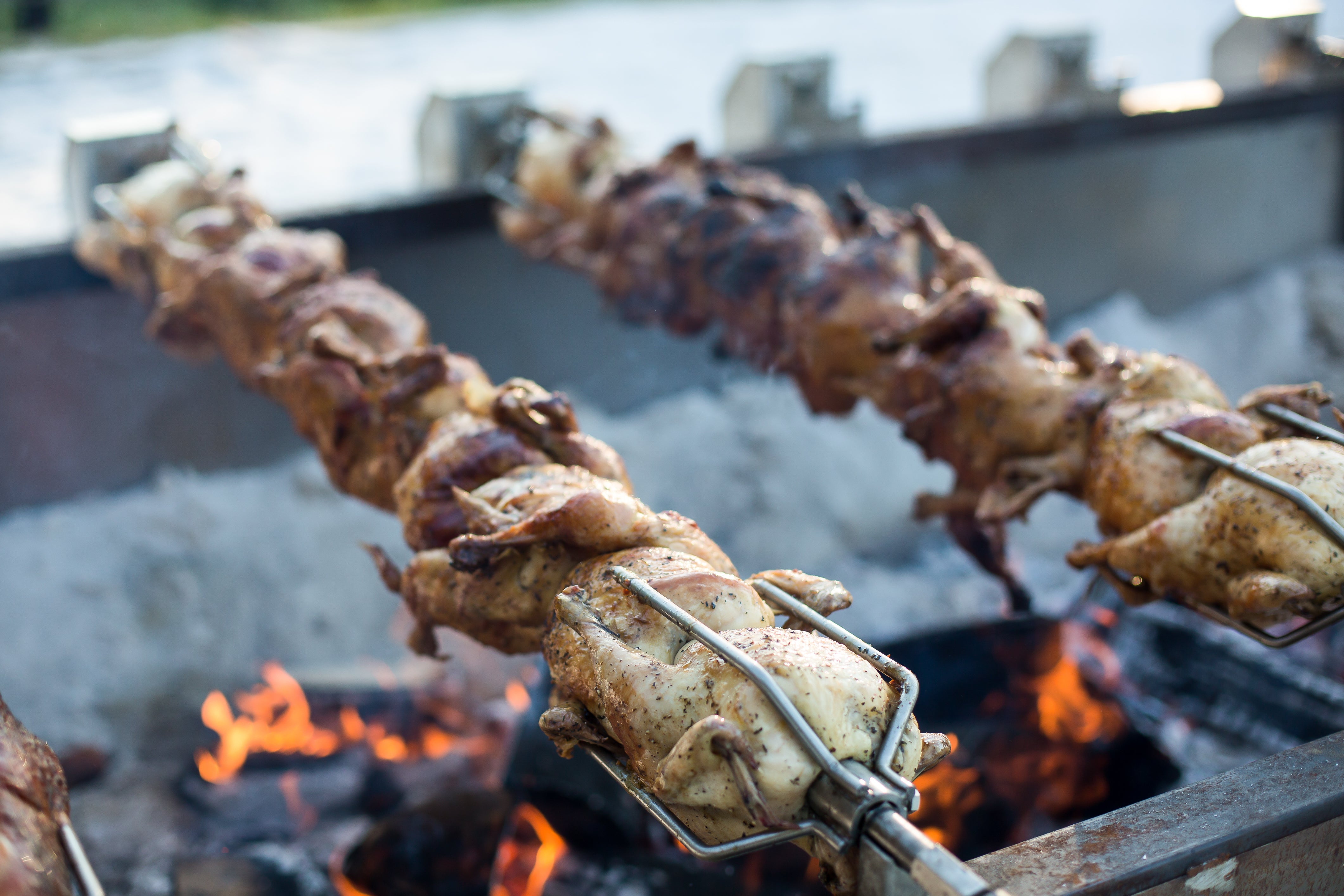 Grill rotisserie chicken over open fire