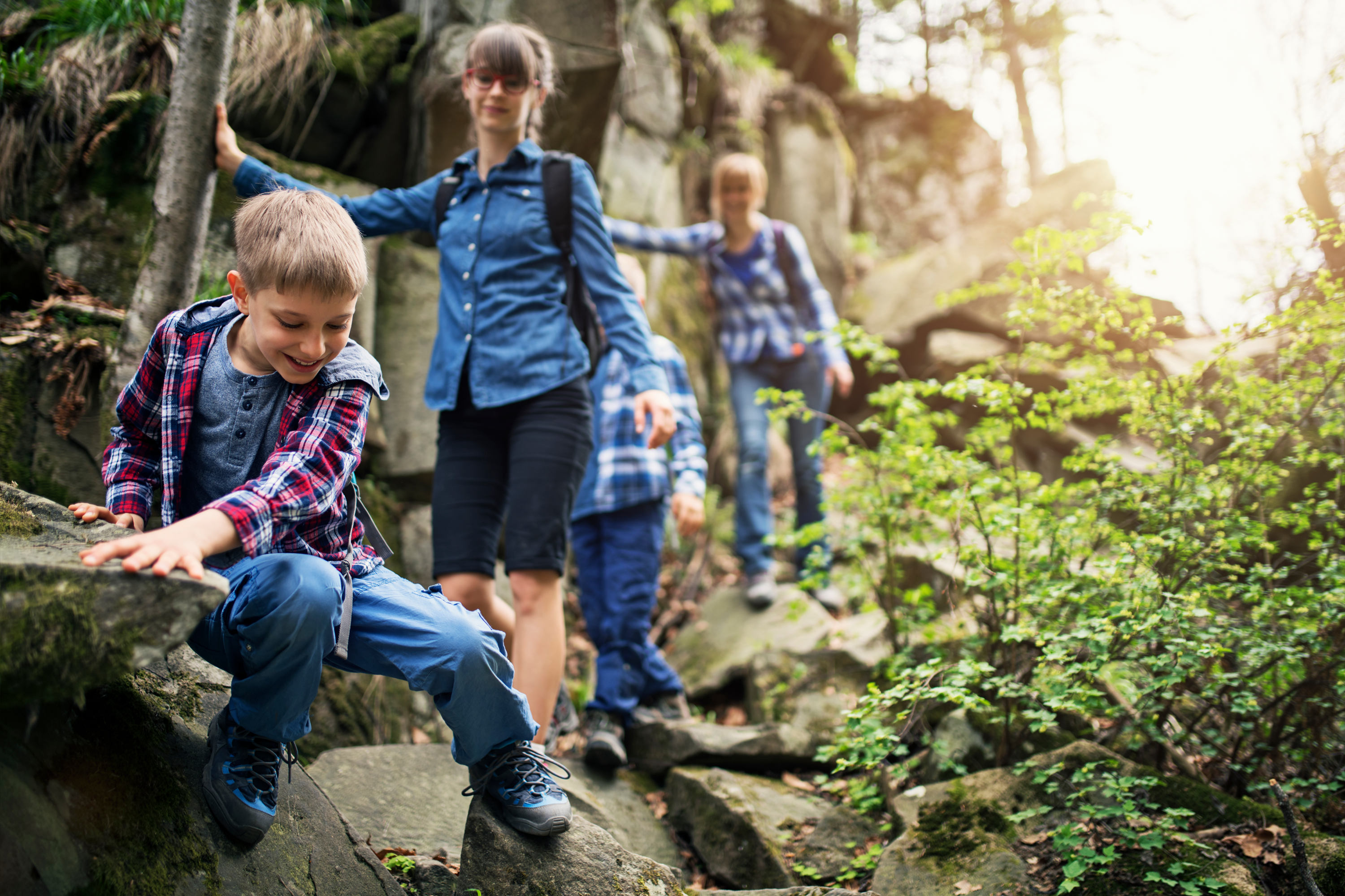 Kids crawling on rocks during family hike.