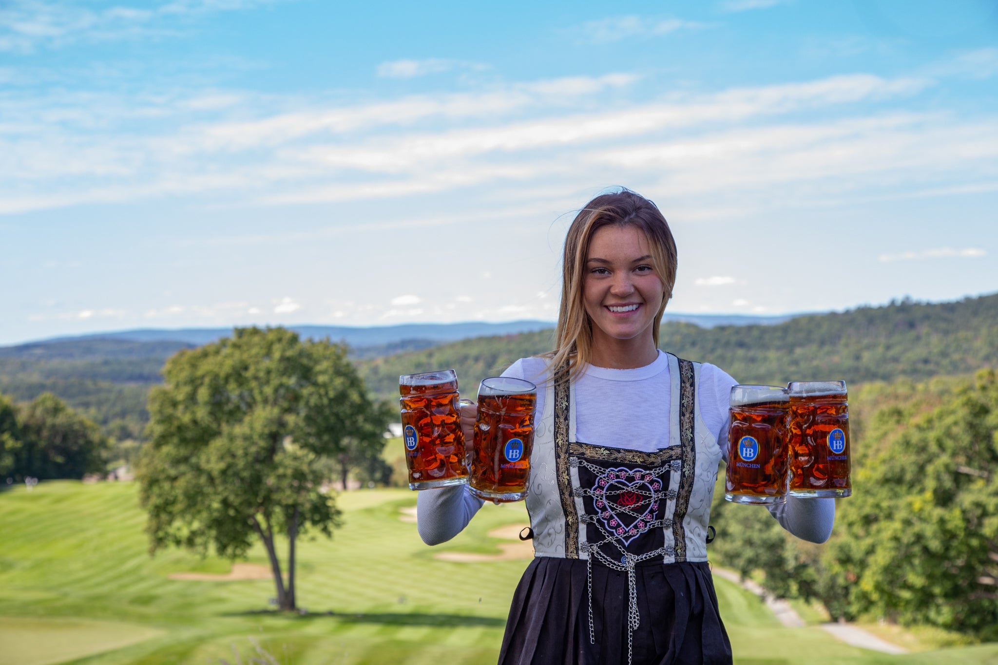 Biergarten bartender holding four steins of beer