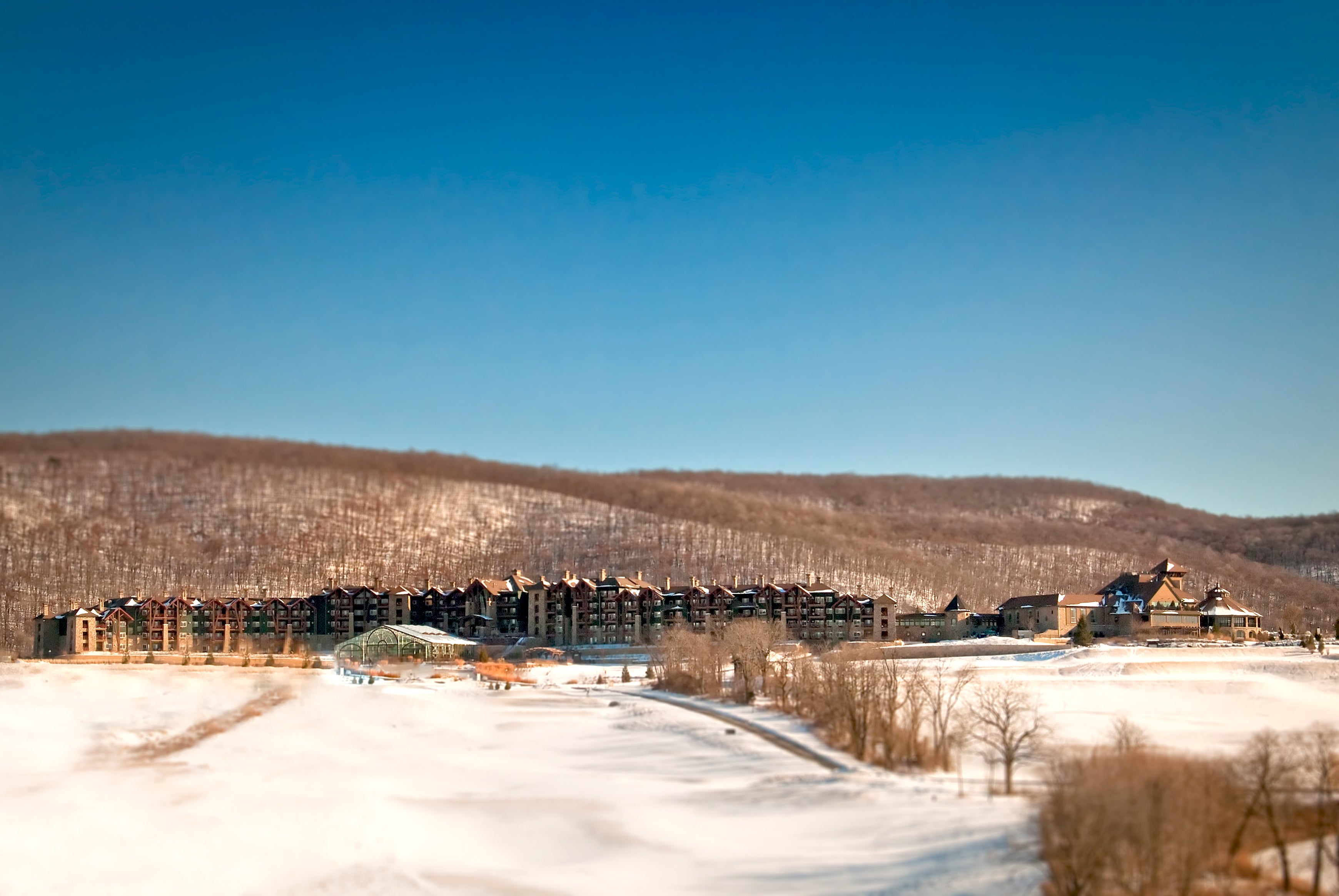 Distant view of Grand Cascades Lodge in front of the snowy mountains