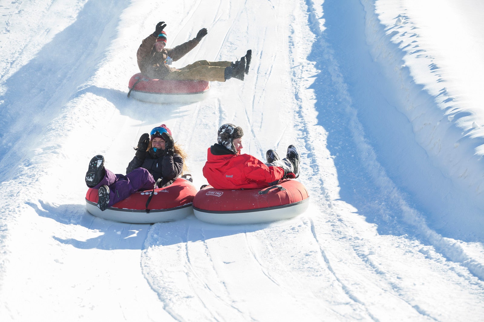 Family snow tubing down mountain.