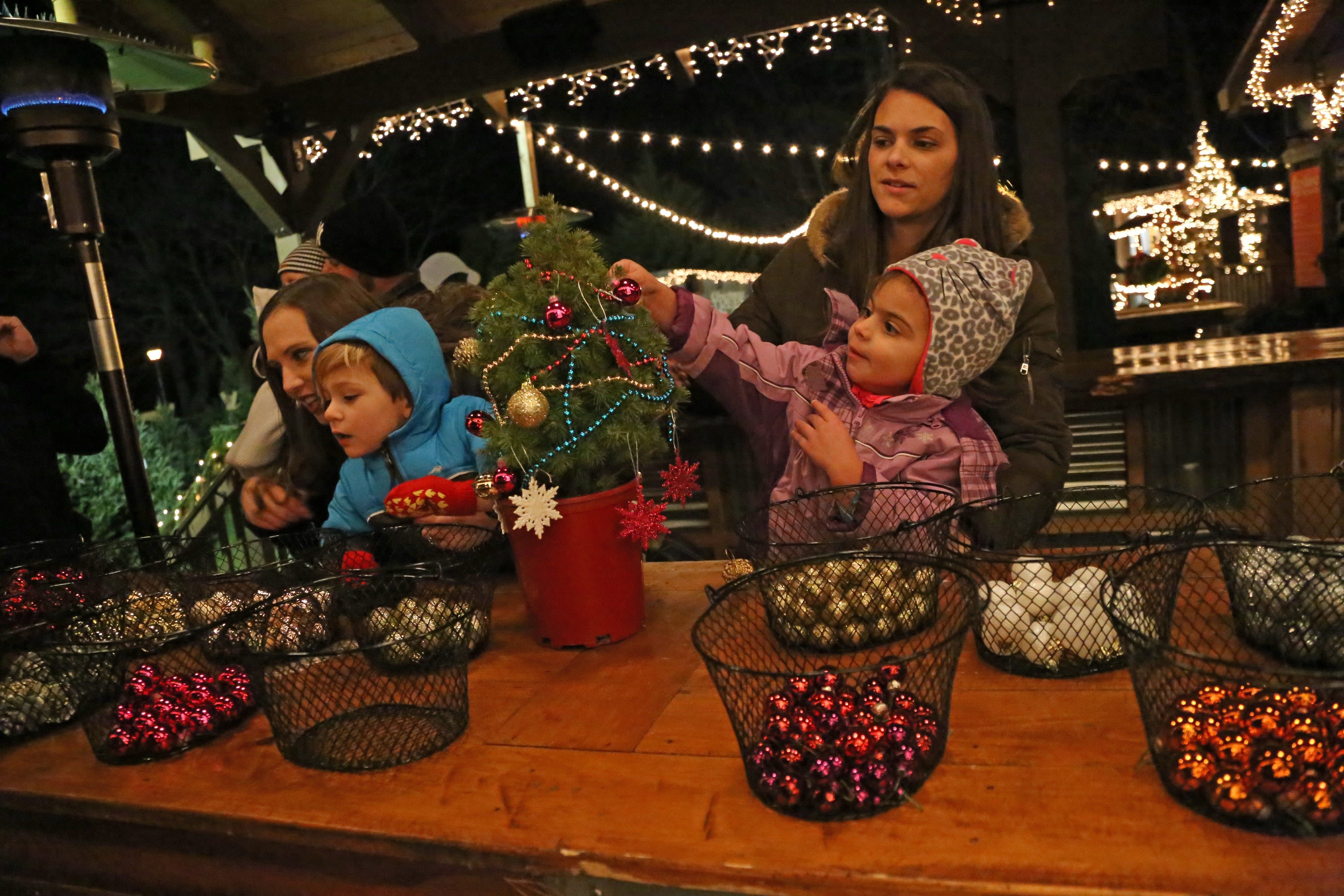 Young children decorating mini trees with bulbs.