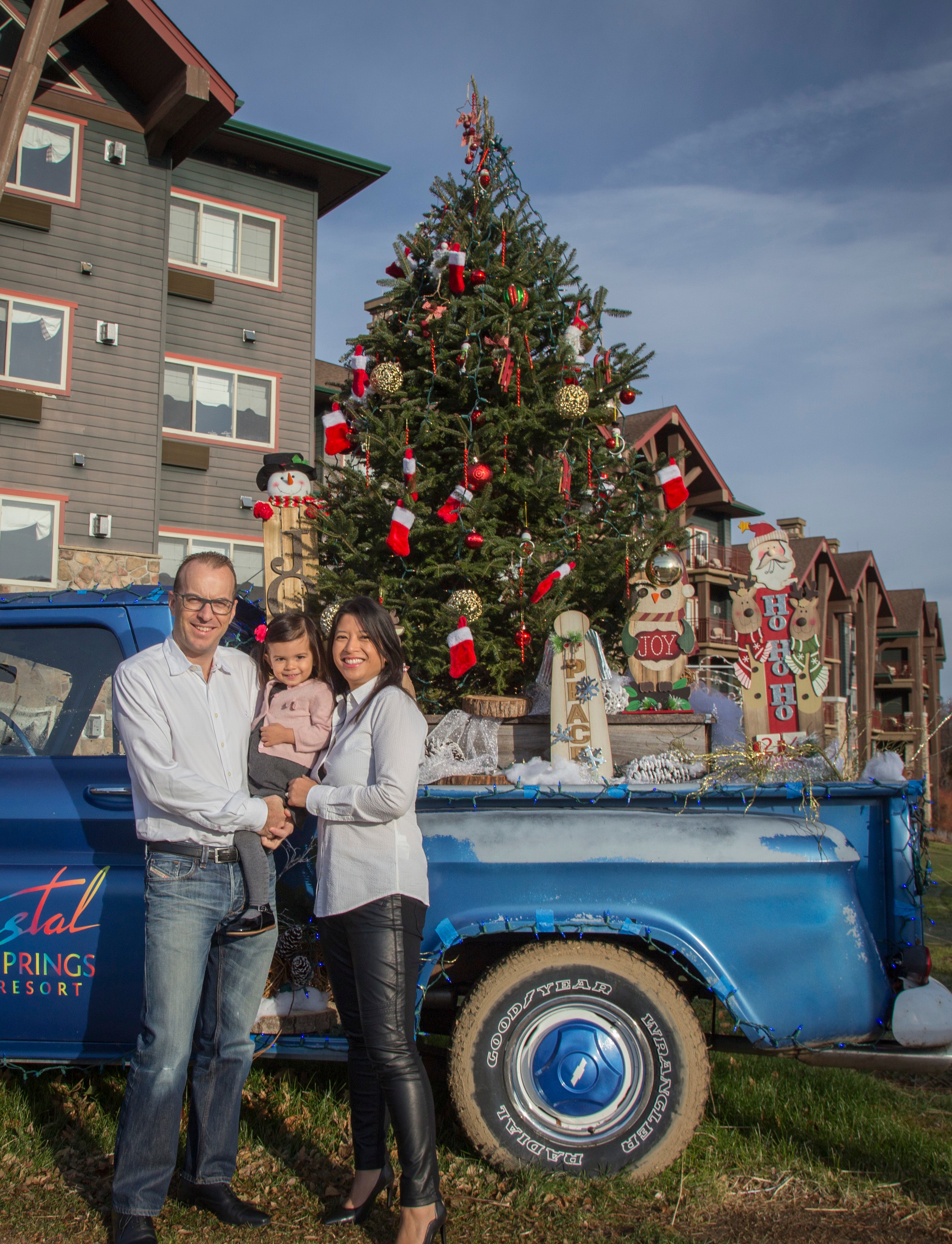 Parents and young daughter at decorative Christmas resort truck at Grand Cascades Lodge