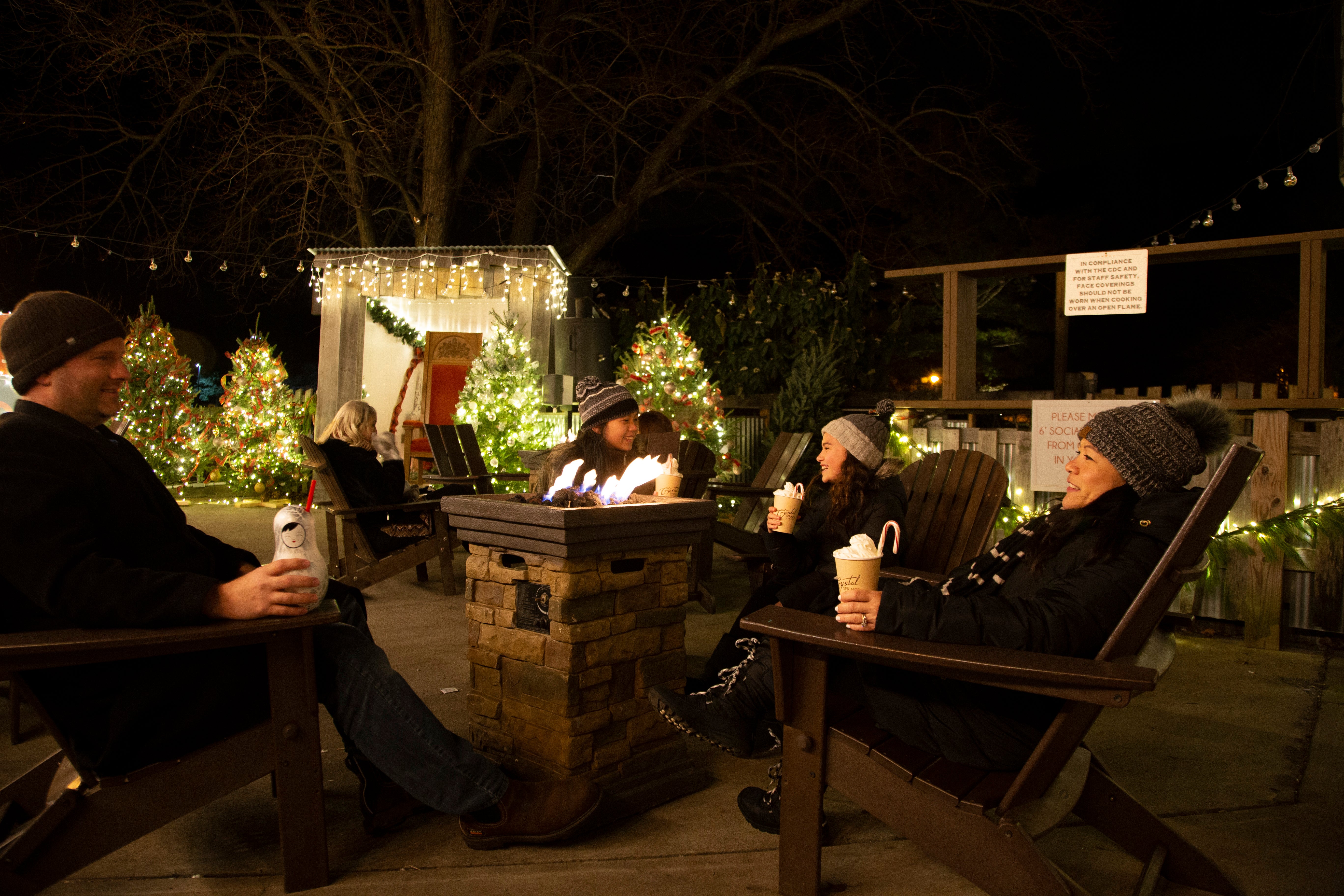 Family of four drinking festive drinks around fire at Frosty's Cantina.