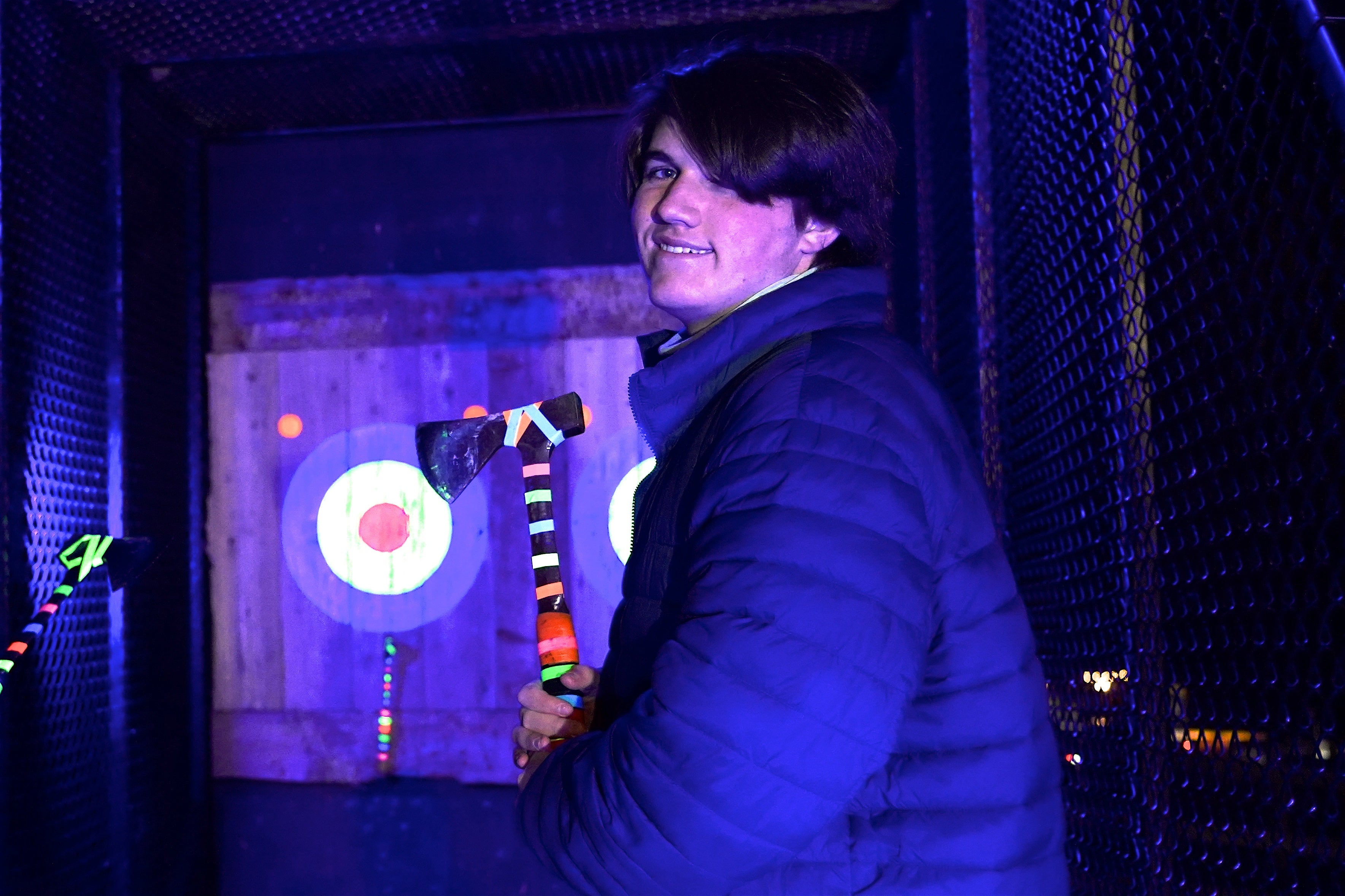 Man holding axe for glow in the dark axe throwing.