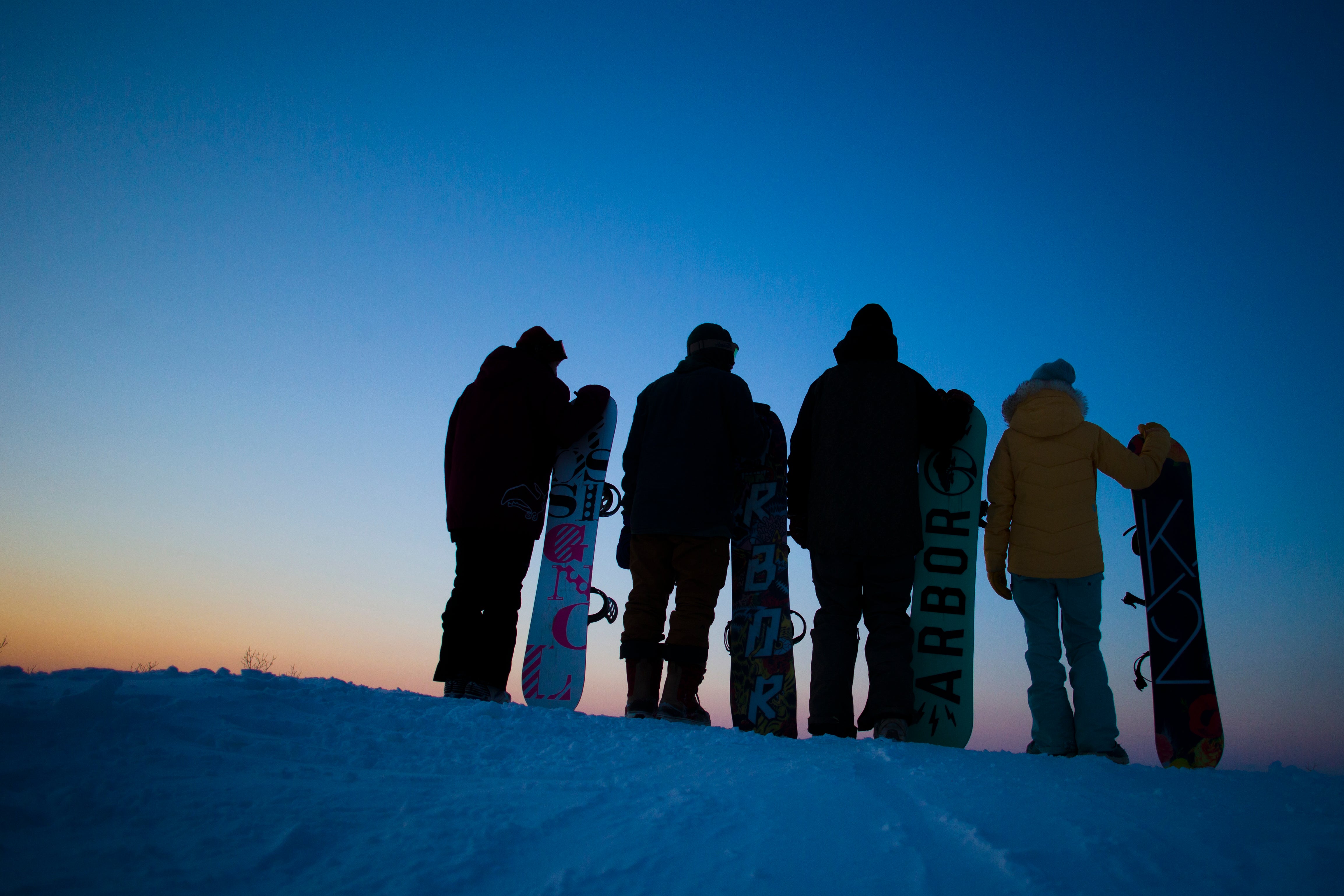Group of snowboarders looking at sunset.