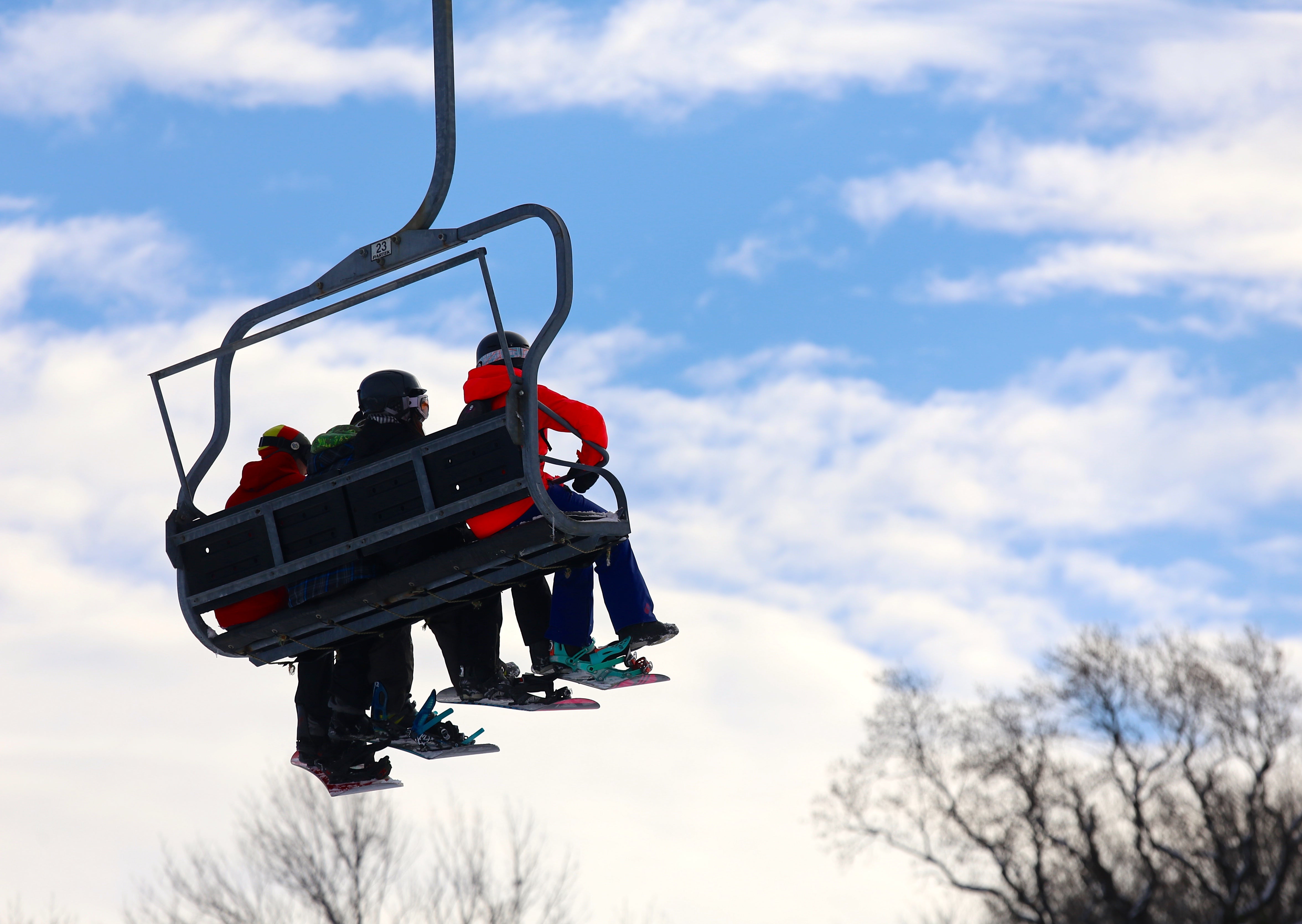 Three people sitting on ski lift.