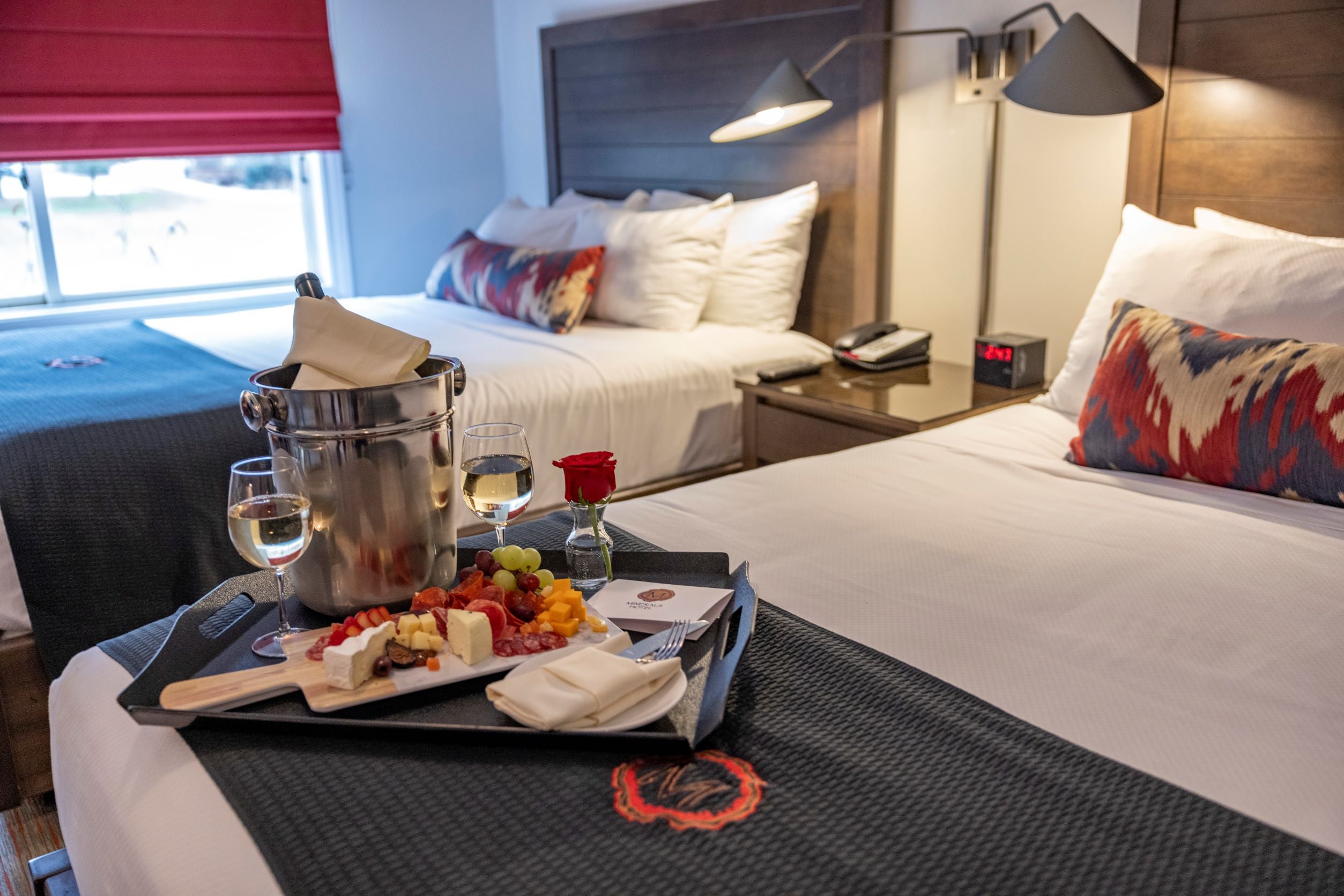 Wine and charcuterie board set on guest bed in deluxe room at Minerals Hotel