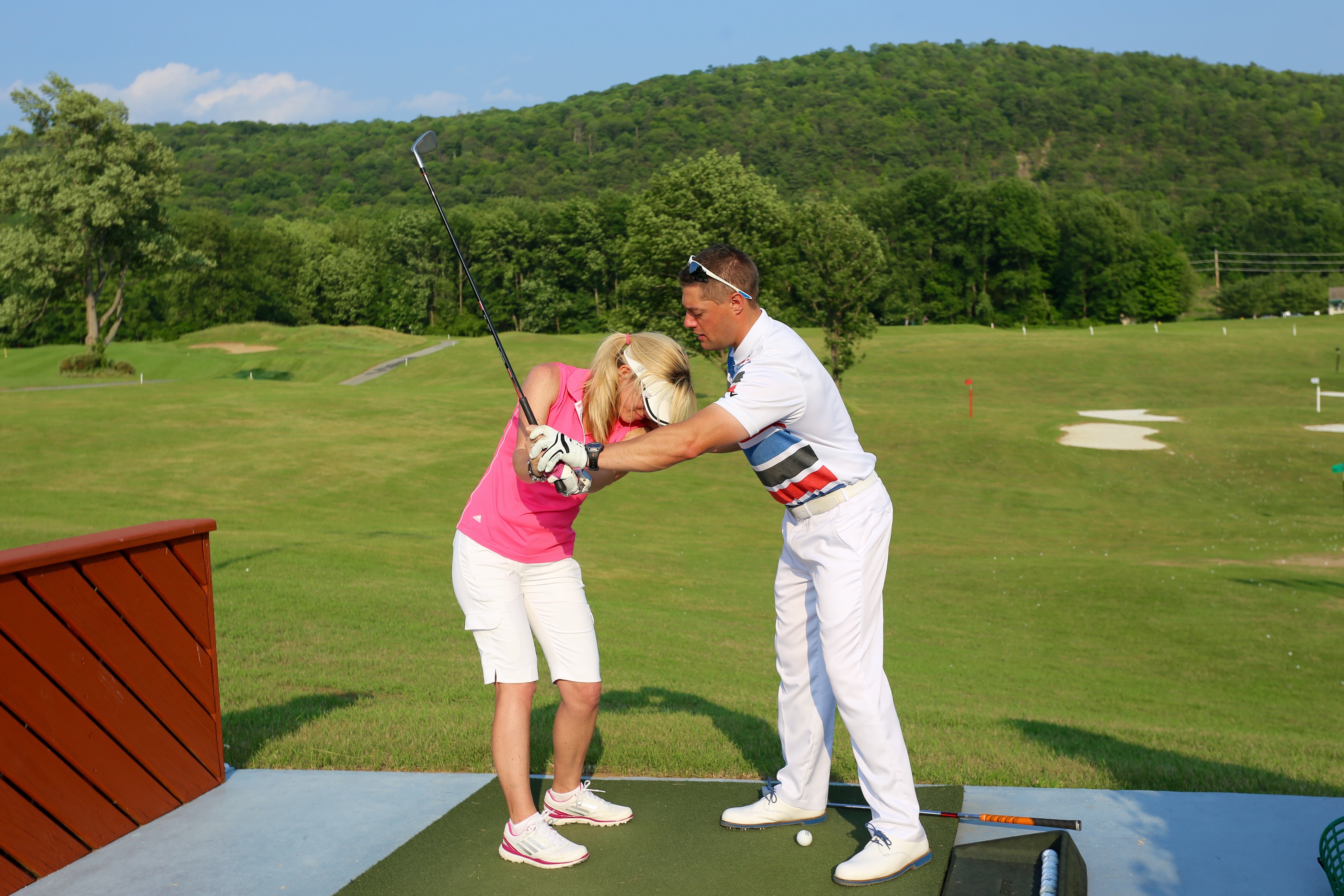 Golf instructor teaching a women to golf