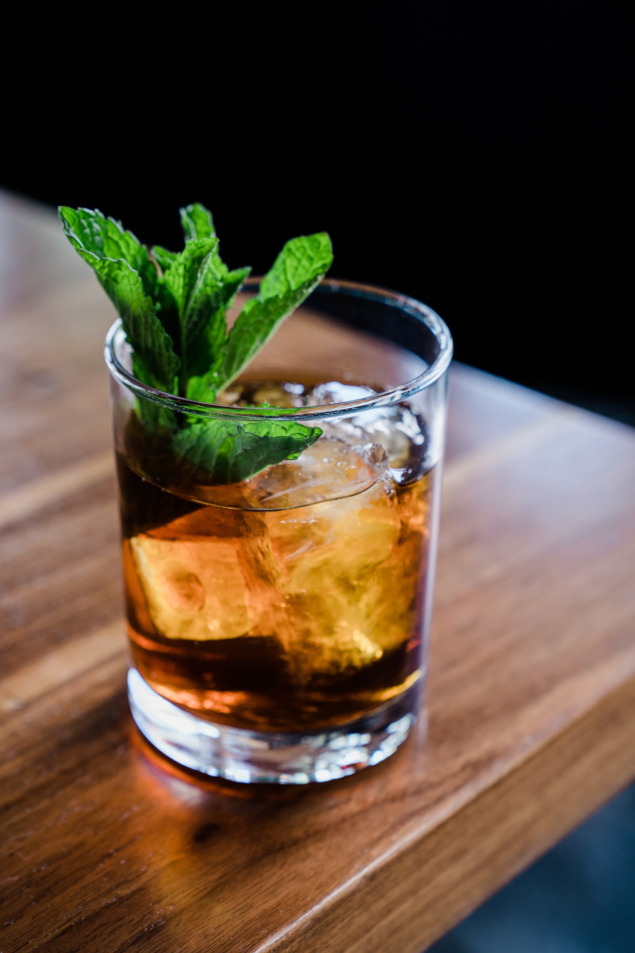 Cocktail in short round glass topped with mint. 