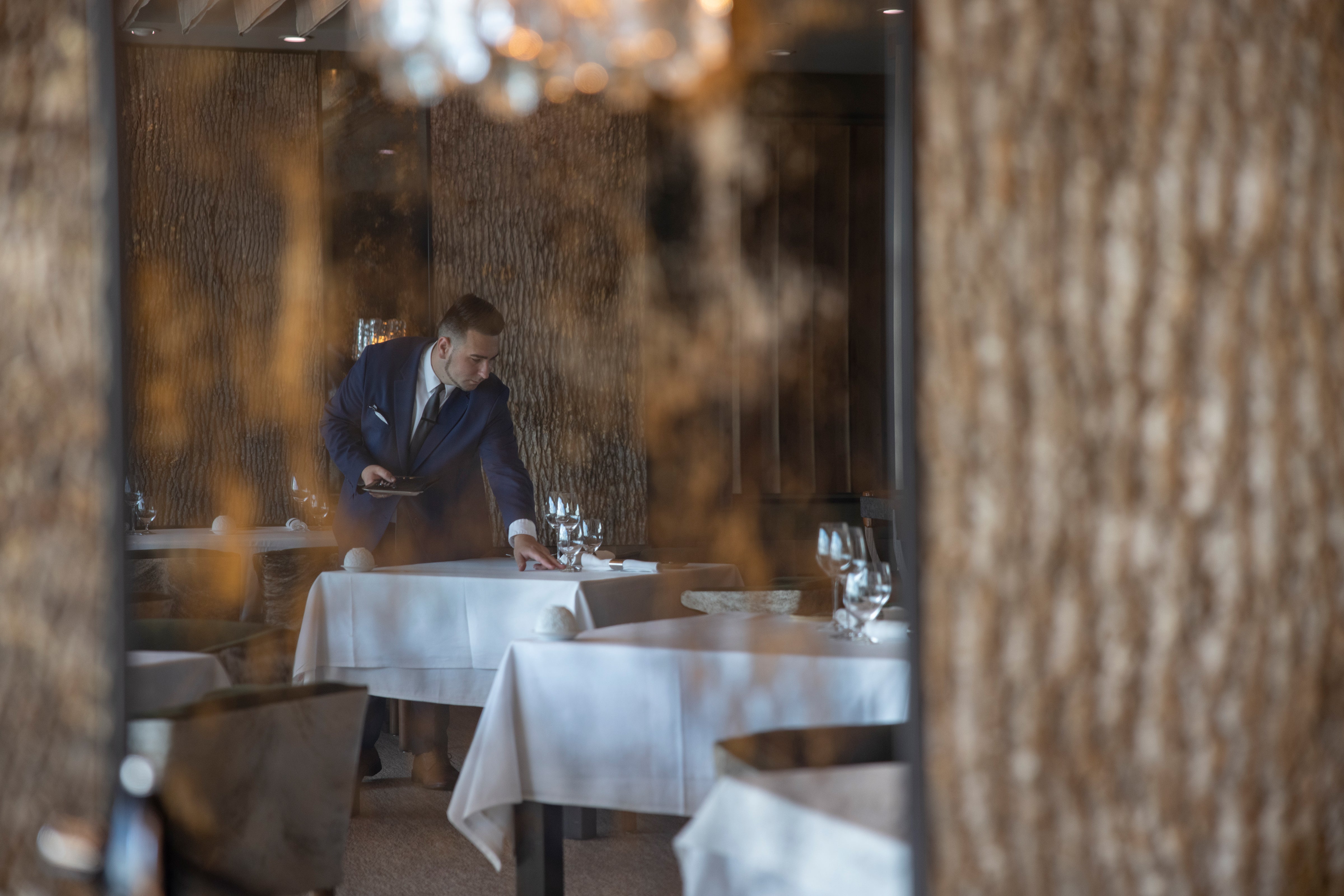 Waiter setting Restaurant Latour tables.