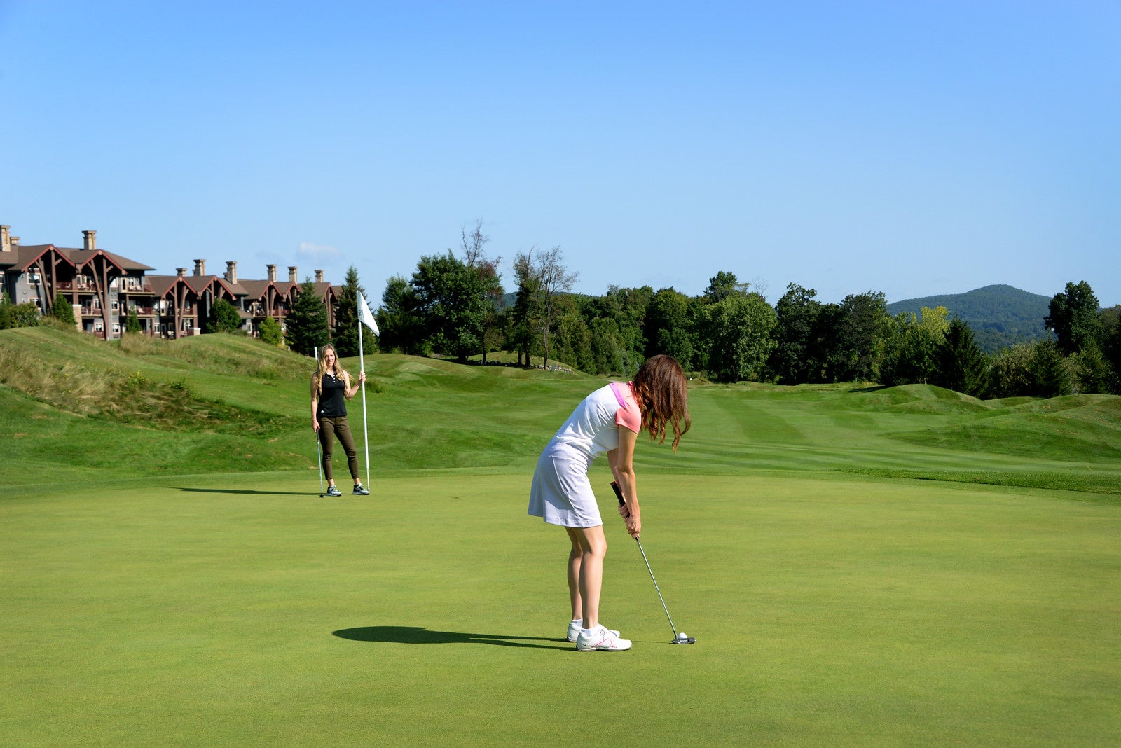 Two women on the green near a hole on a golf course