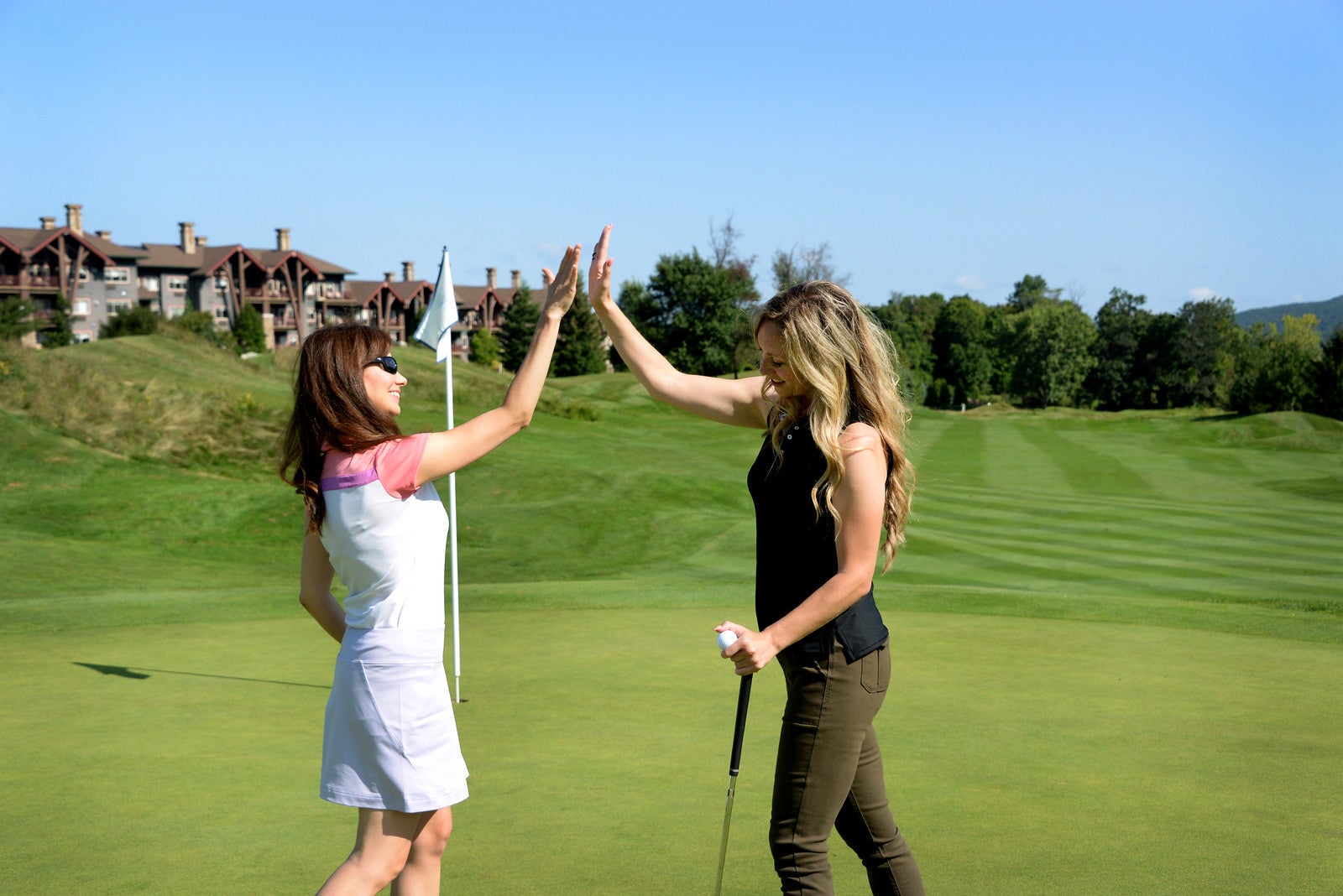 Two women high fiving on a golf course