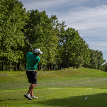 Golfer wearing a green shirt teeing off on Black Bear golf course