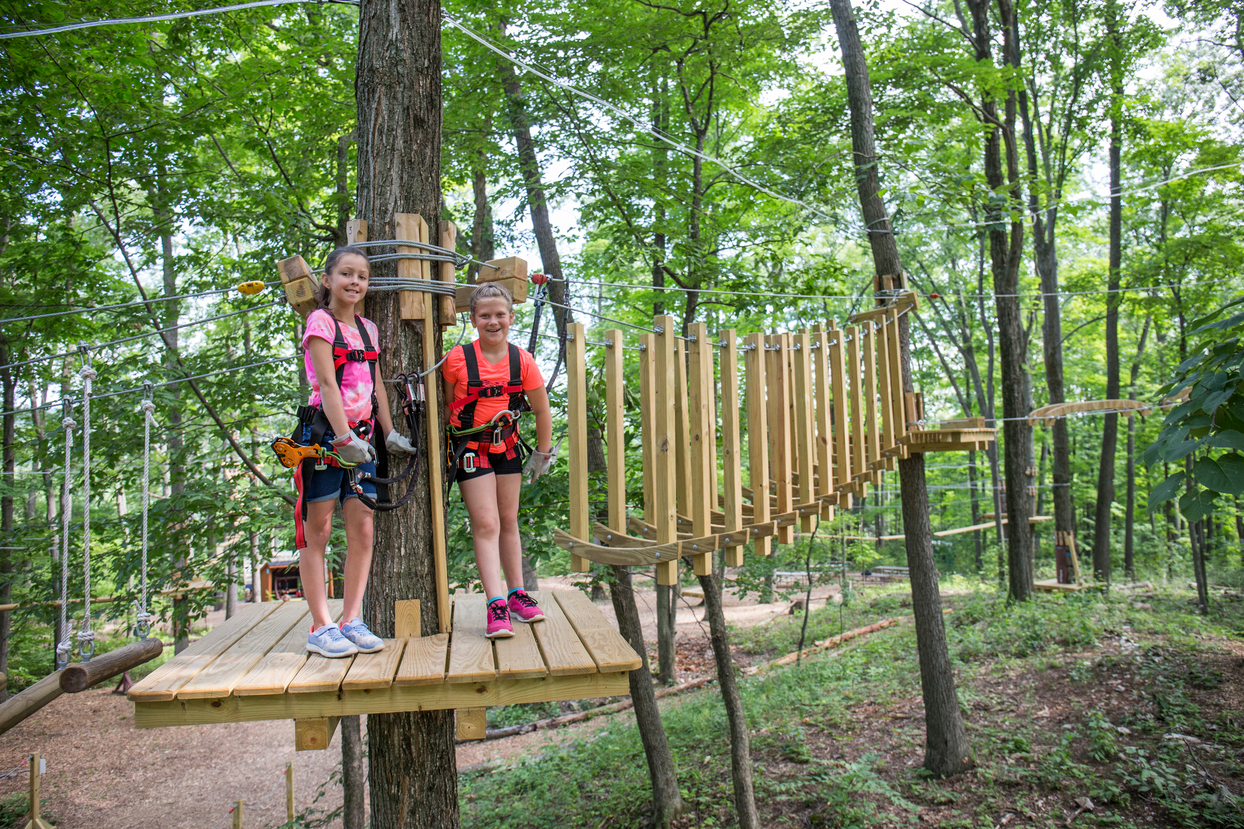 Two girls standing in ropes course gear on their family vacation.