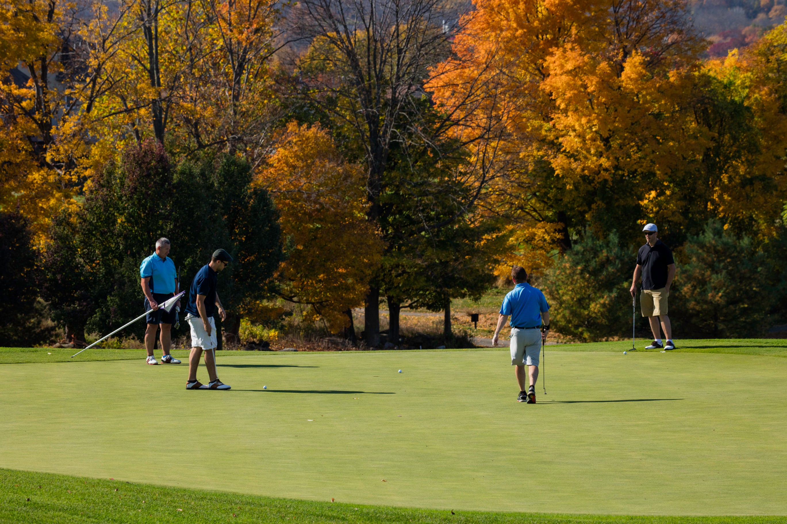 Four guys near a hole on a golf course at Crystal Springs Resort