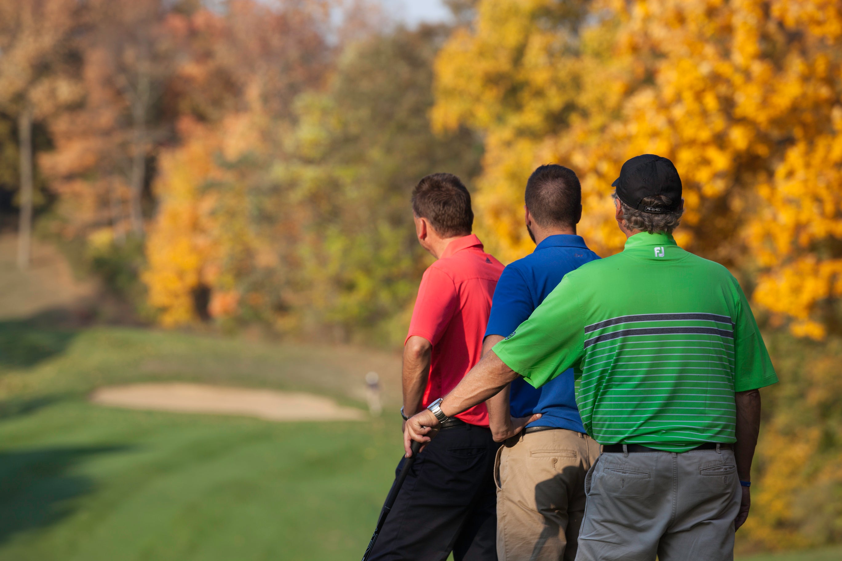 Golfers playing in fall looking over the golf course