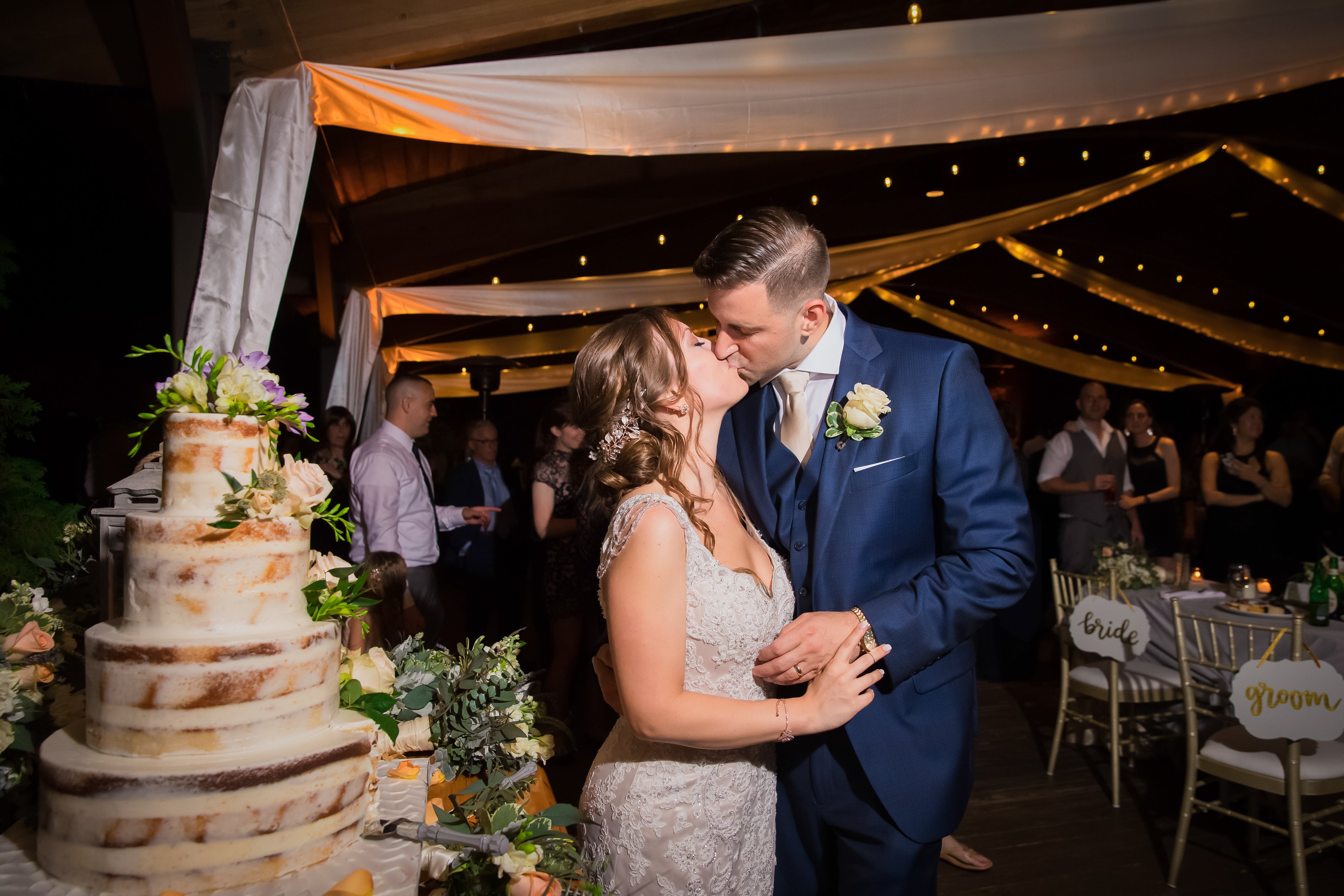 Bride and Groom kissing next to the wedding cake