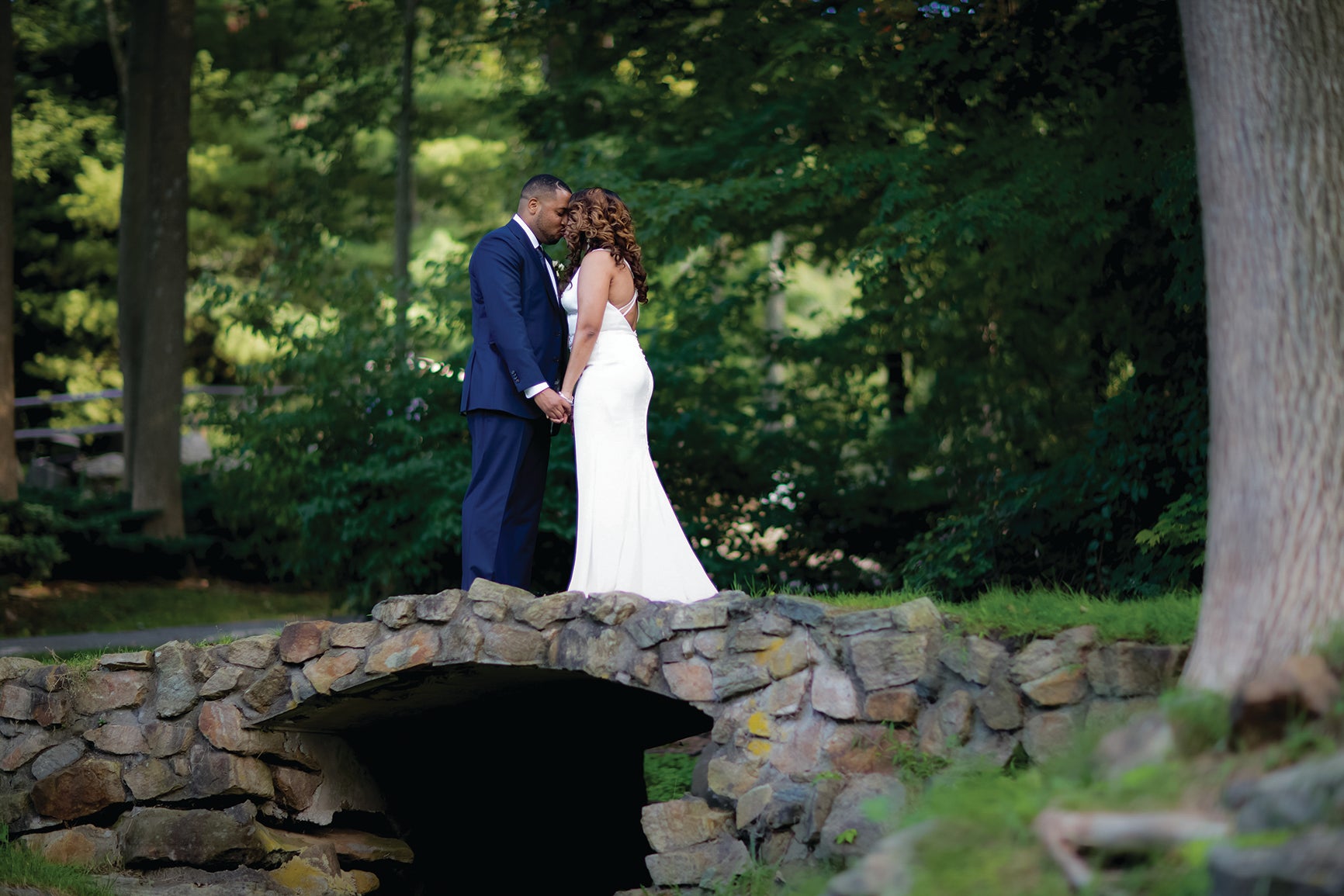 Bride and groom standing over bridge holding hands