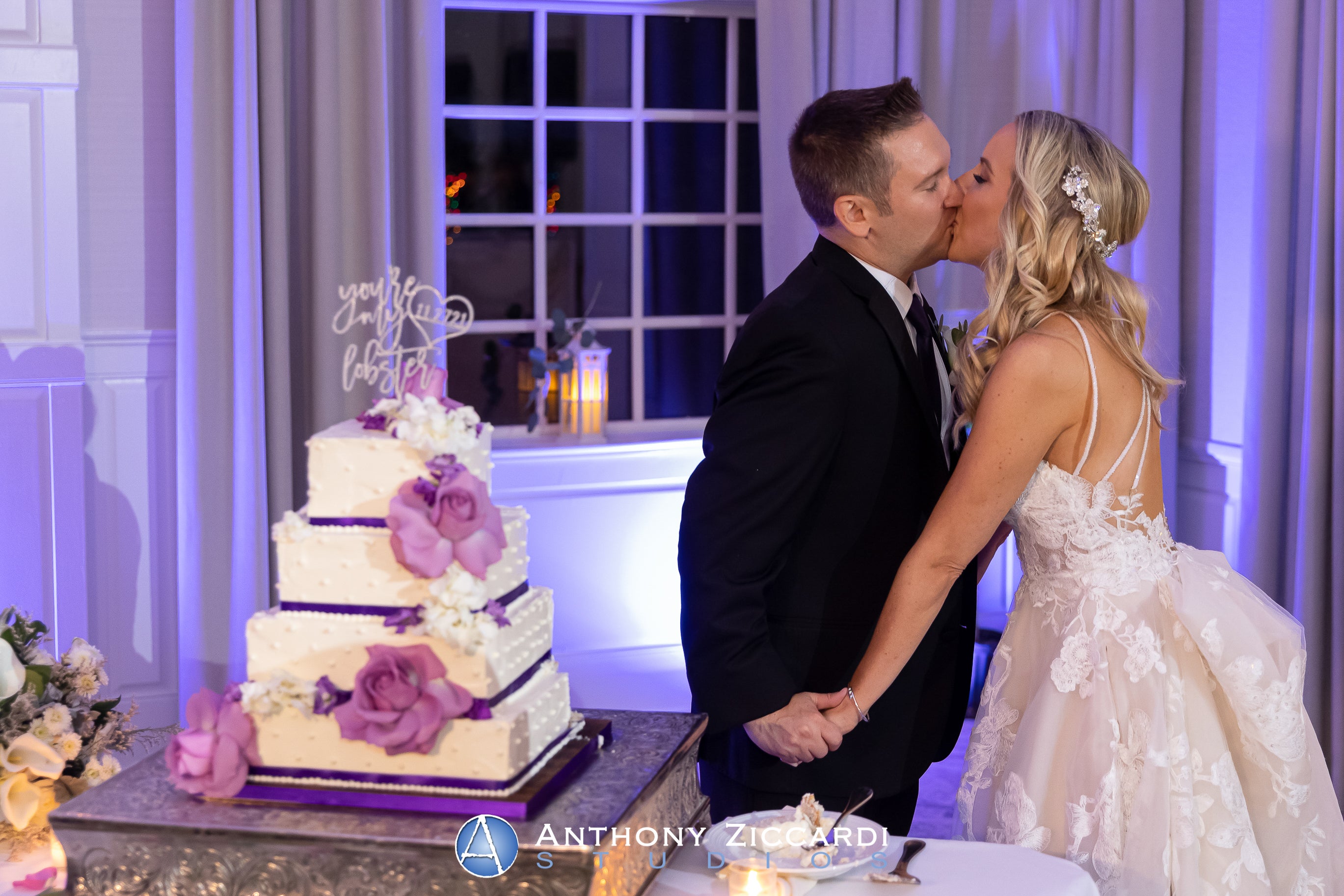 Bride and Groom kissing by wedding cake