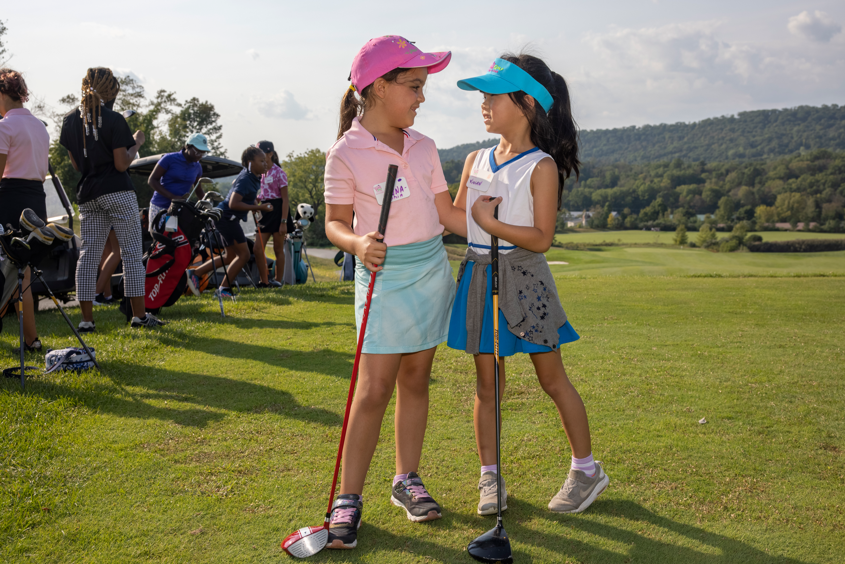 Two girls smiling at each other, learning to golf at Crystal Springs Resort