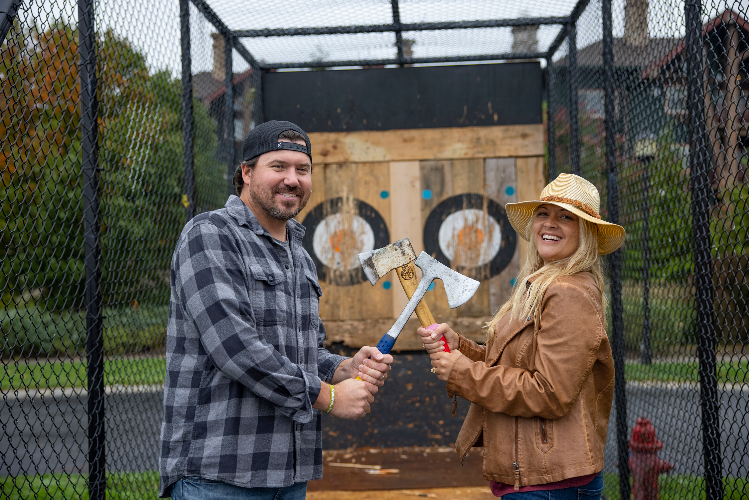 Woman and man holding axes in front of axe throwing target during couples getaway.