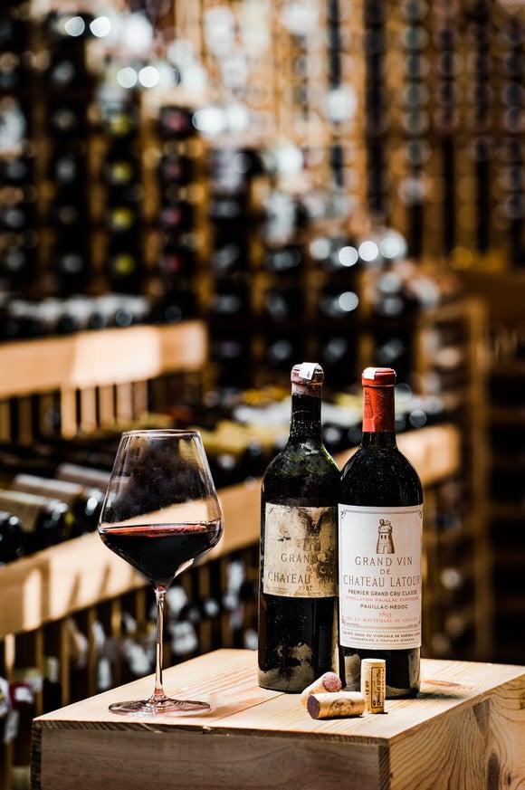 Two bottles of wine and glass of wine set up wooden box.
