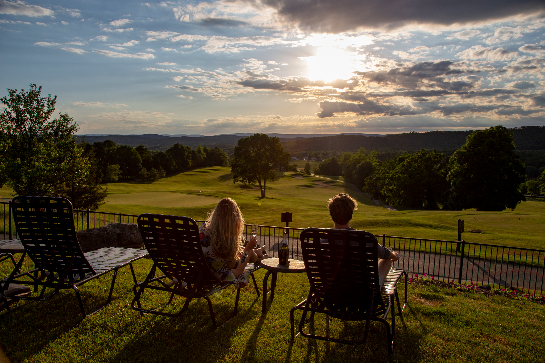 Woman and man sitting in lounge chairs looking at a sunset.