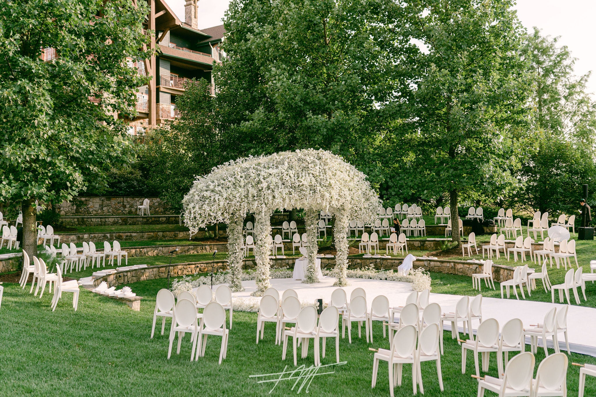 Wedding ceremony in amphitheater with white chairs and white flowers. 